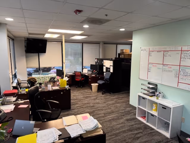 Office workspace with desks, computers, chairs, and a whiteboard inside BAYADA Adult Nursing.
