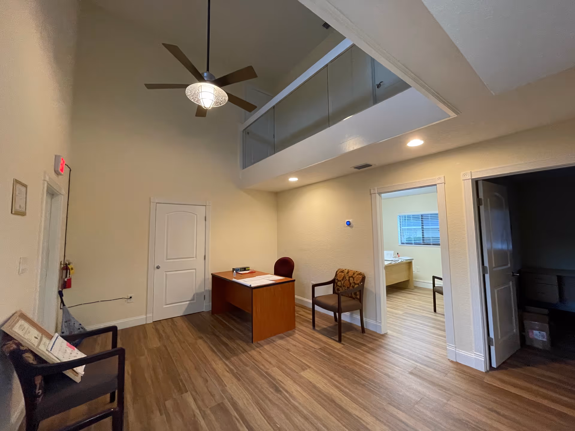 Reception desk and chairs in a spacious interior with an adjacent room showing a bed.