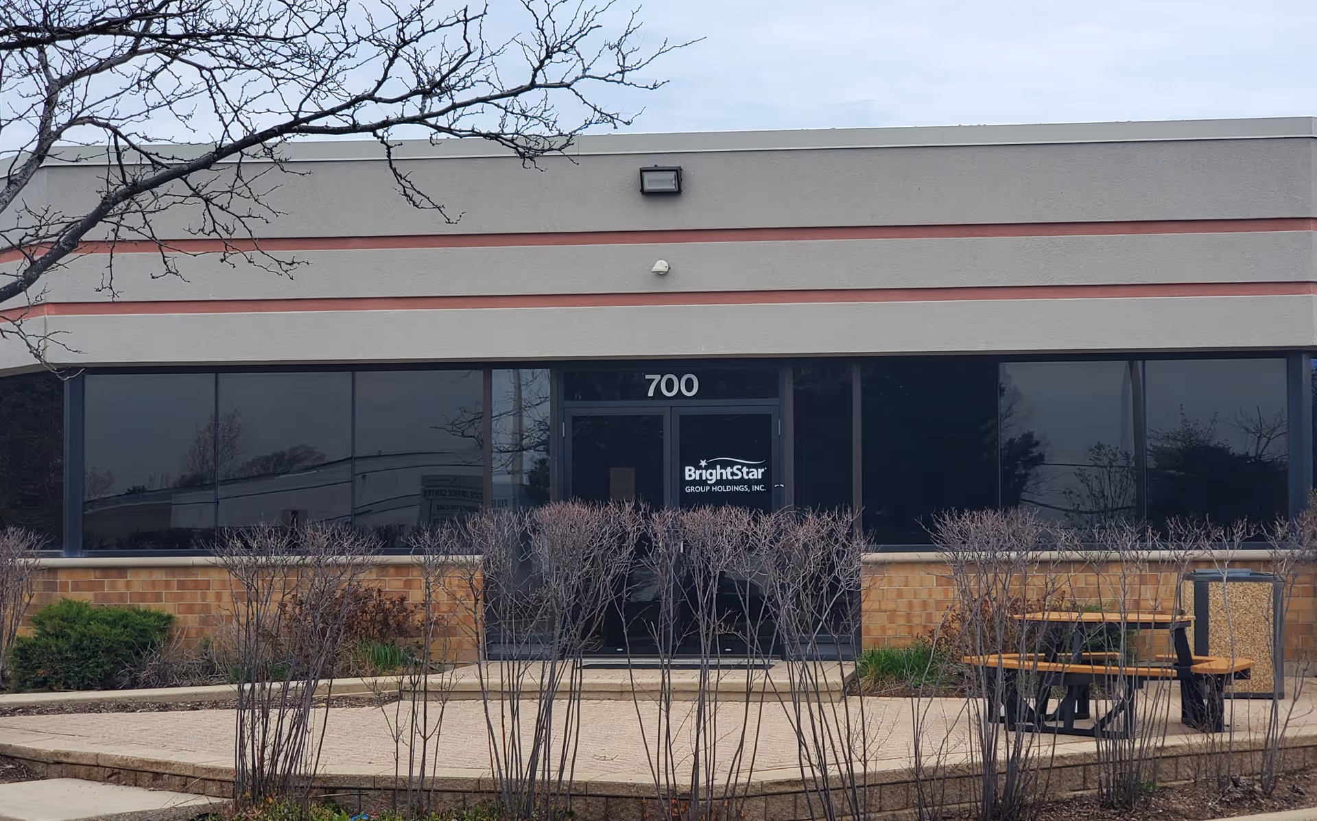 Front entrance of BrightStar Care building with large windows and seating outside.
