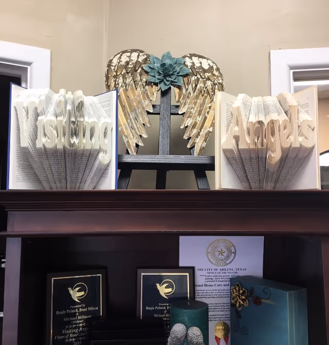 Decorative shelf display with 'Visiting Angels' lettering and angel wing sculpture.
