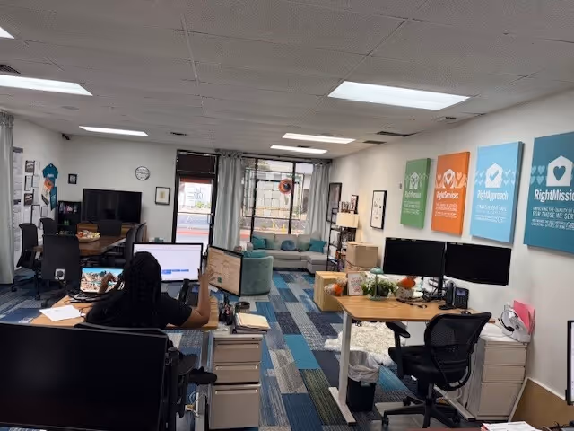 Bright interior office and common area with desks, computers, couches, and colorful wall signs.