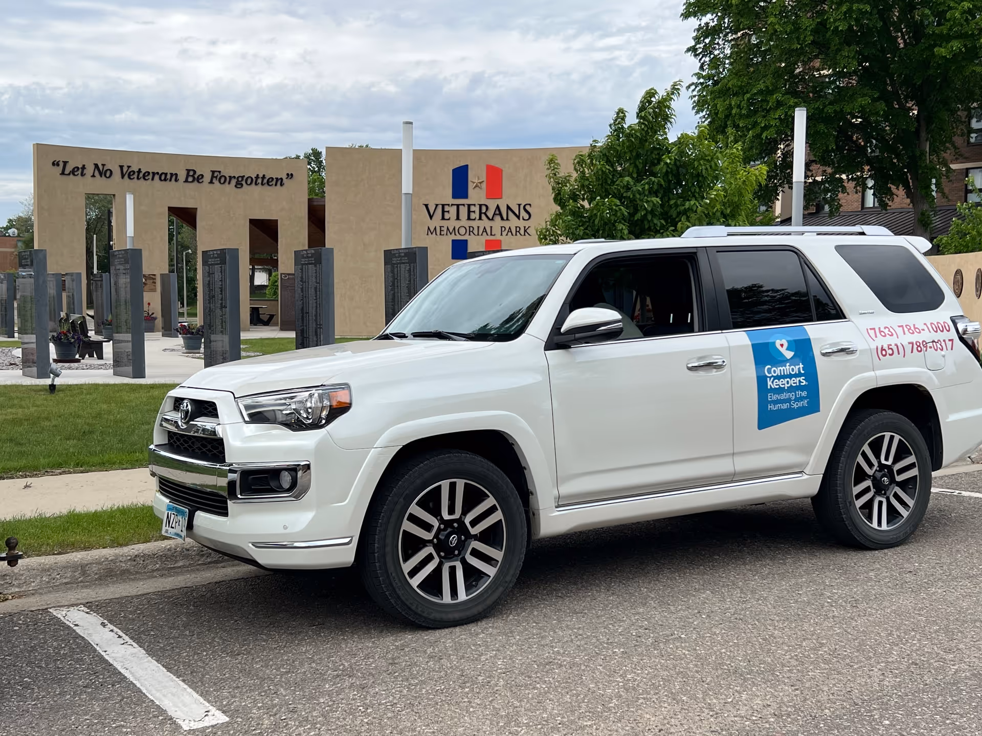 White Comfort Keepers SUV parked on street near Veterans Memorial Park sign