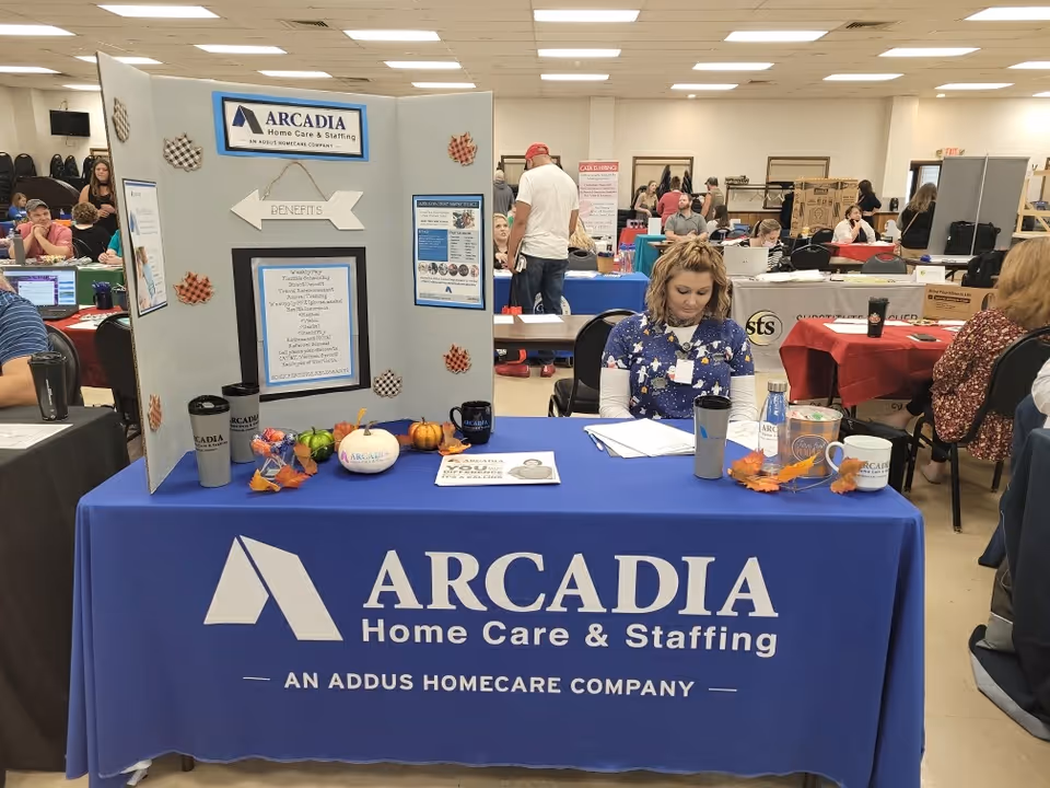 Arcadia Home Care & Staffing booth at an indoor event with staff and attendees.