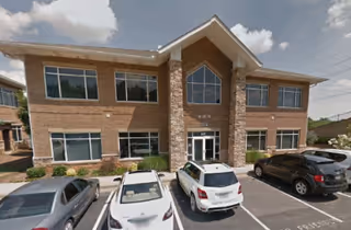 Two-story brick facility with stone accents and a small parking lot in front.