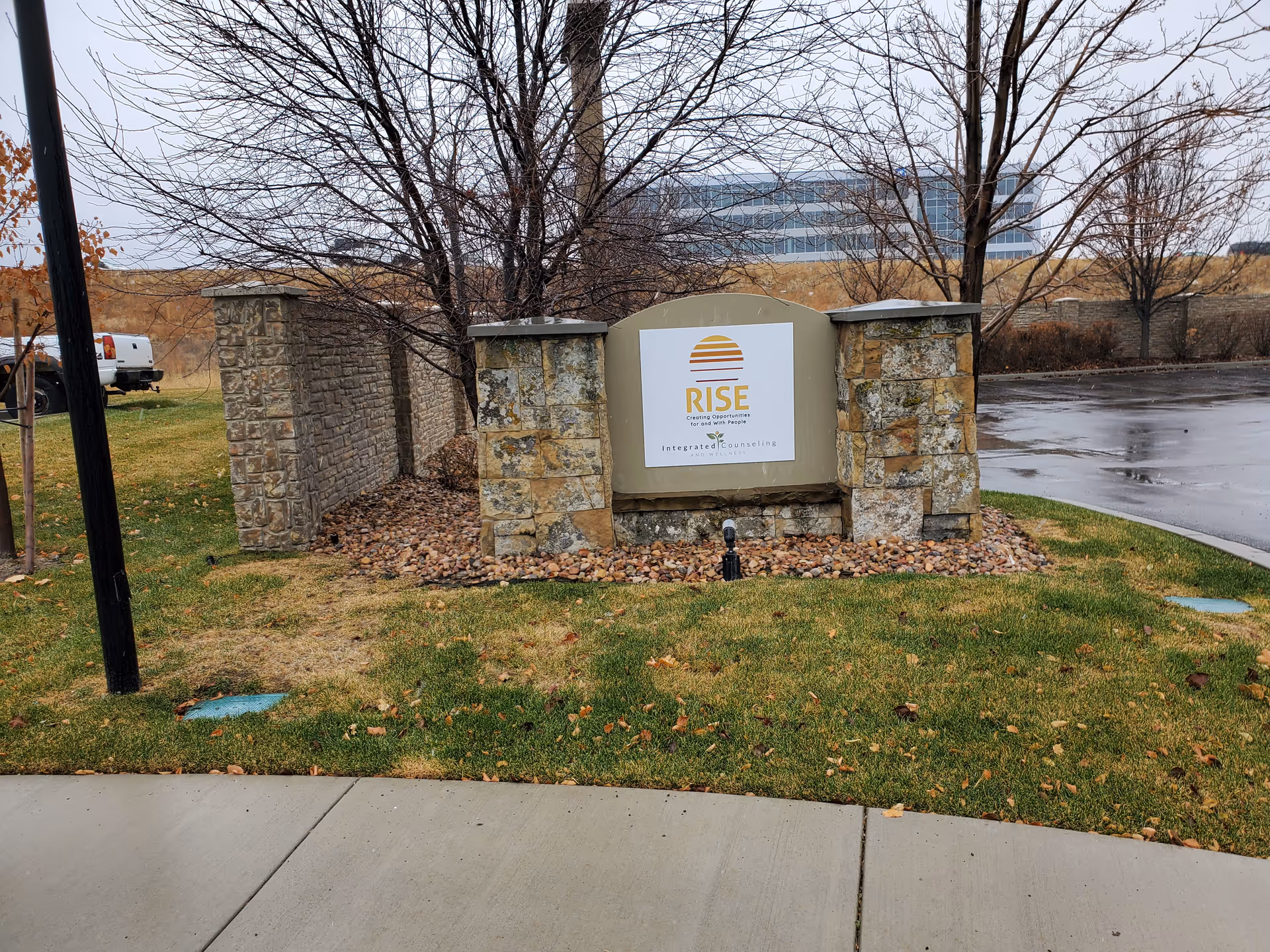 Stone RISE Services, Inc. sign on a landscaped island beside a parking lot.