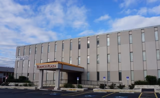 Exterior view of a beige multi-story building with a covered entrance labeled Blanco Plaza.