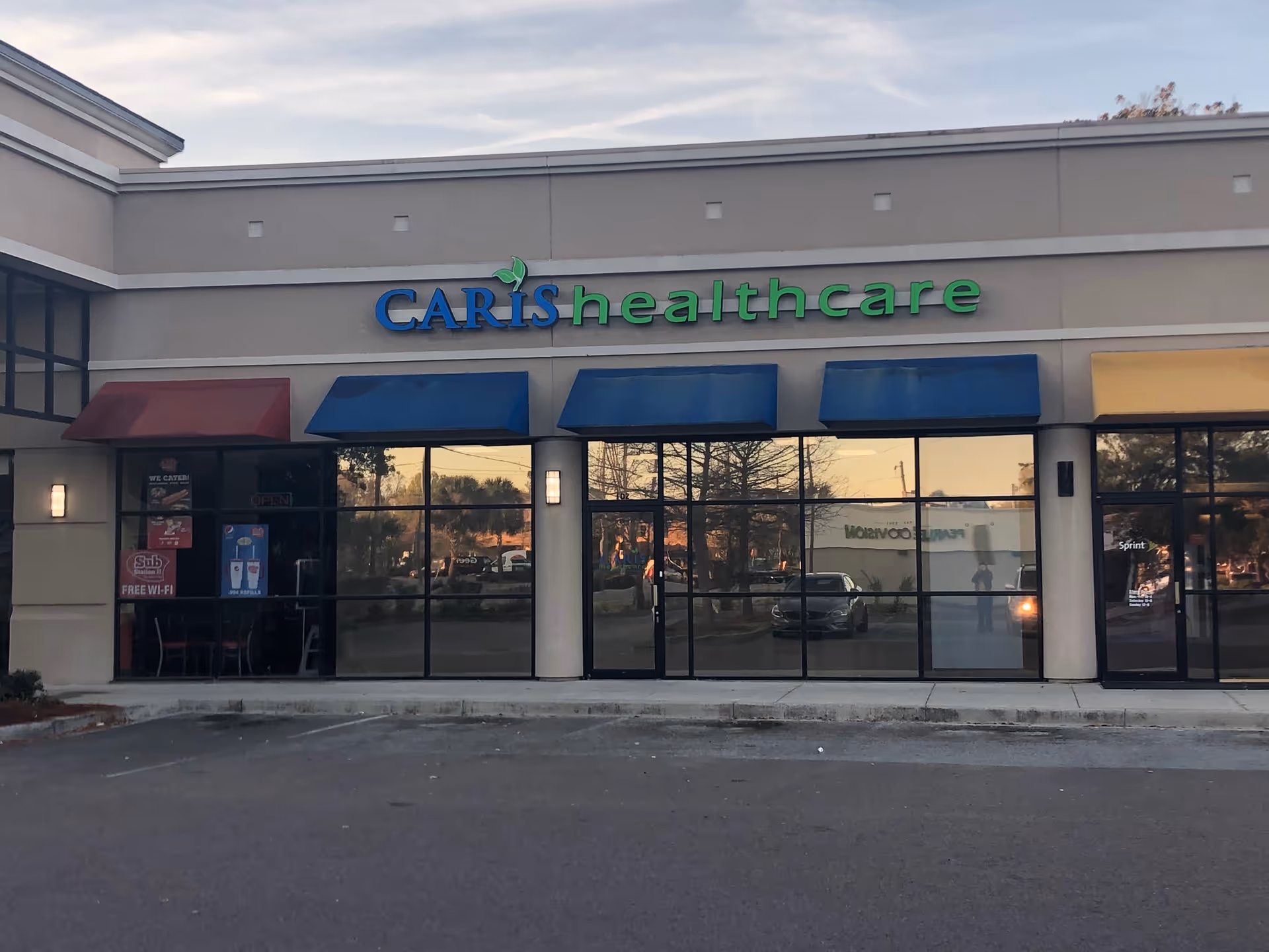 Caris Healthcare storefront with blue awnings and large glass windows.