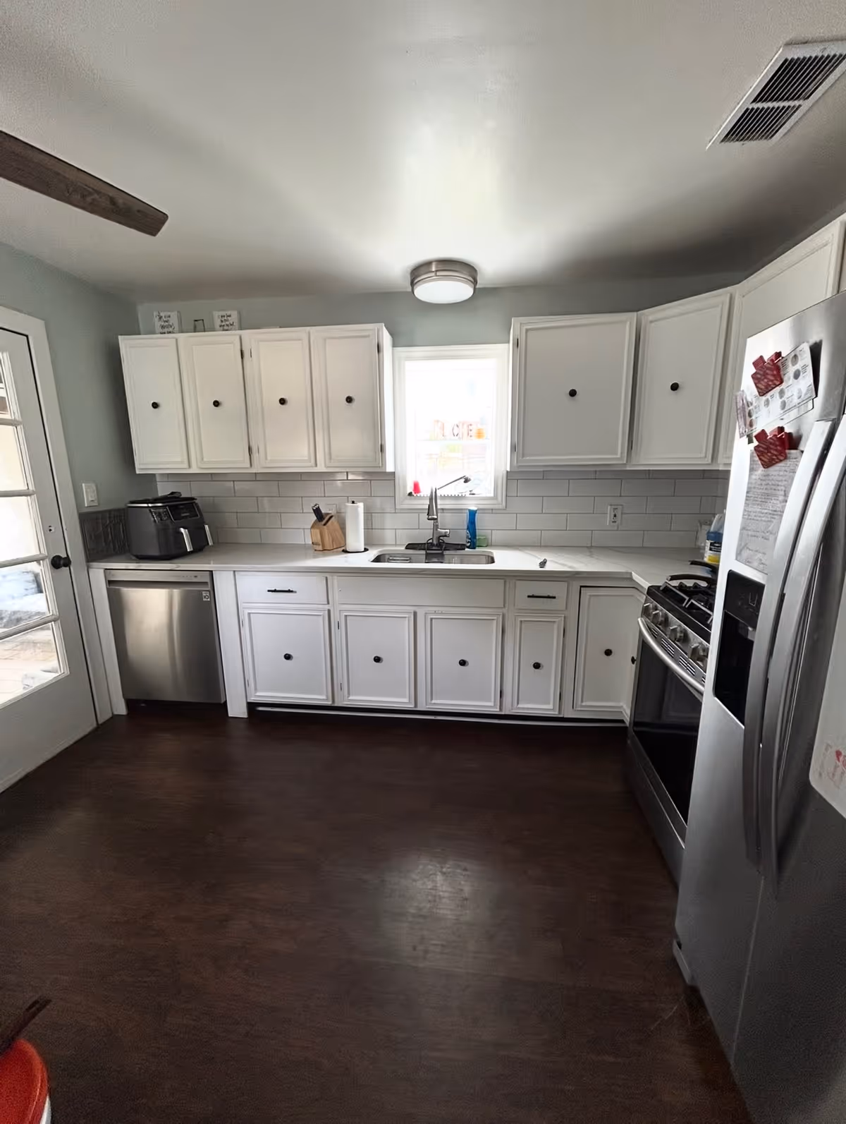 White kitchen with cabinets, sink, dishwasher, fridge, and stove in a senior living facility.