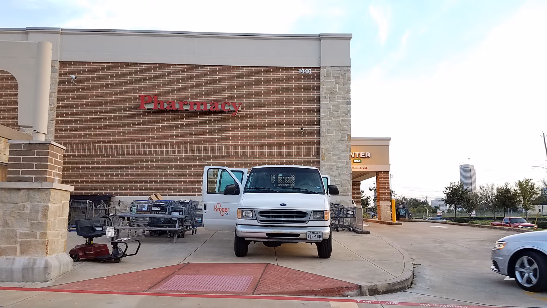 Brick Kroger Pharmacy storefront with a white delivery van and shopping carts in the parking area.