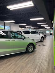 Indoor parking area with several green and white vehicles under bright ceiling lights.