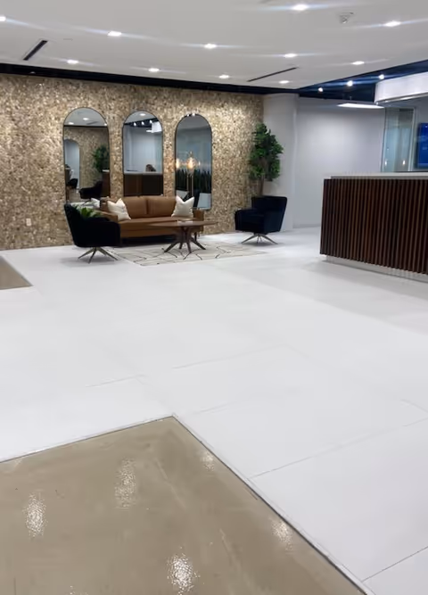 Modern lobby seating area with arched mirrors, a stone accent wall, and plants.