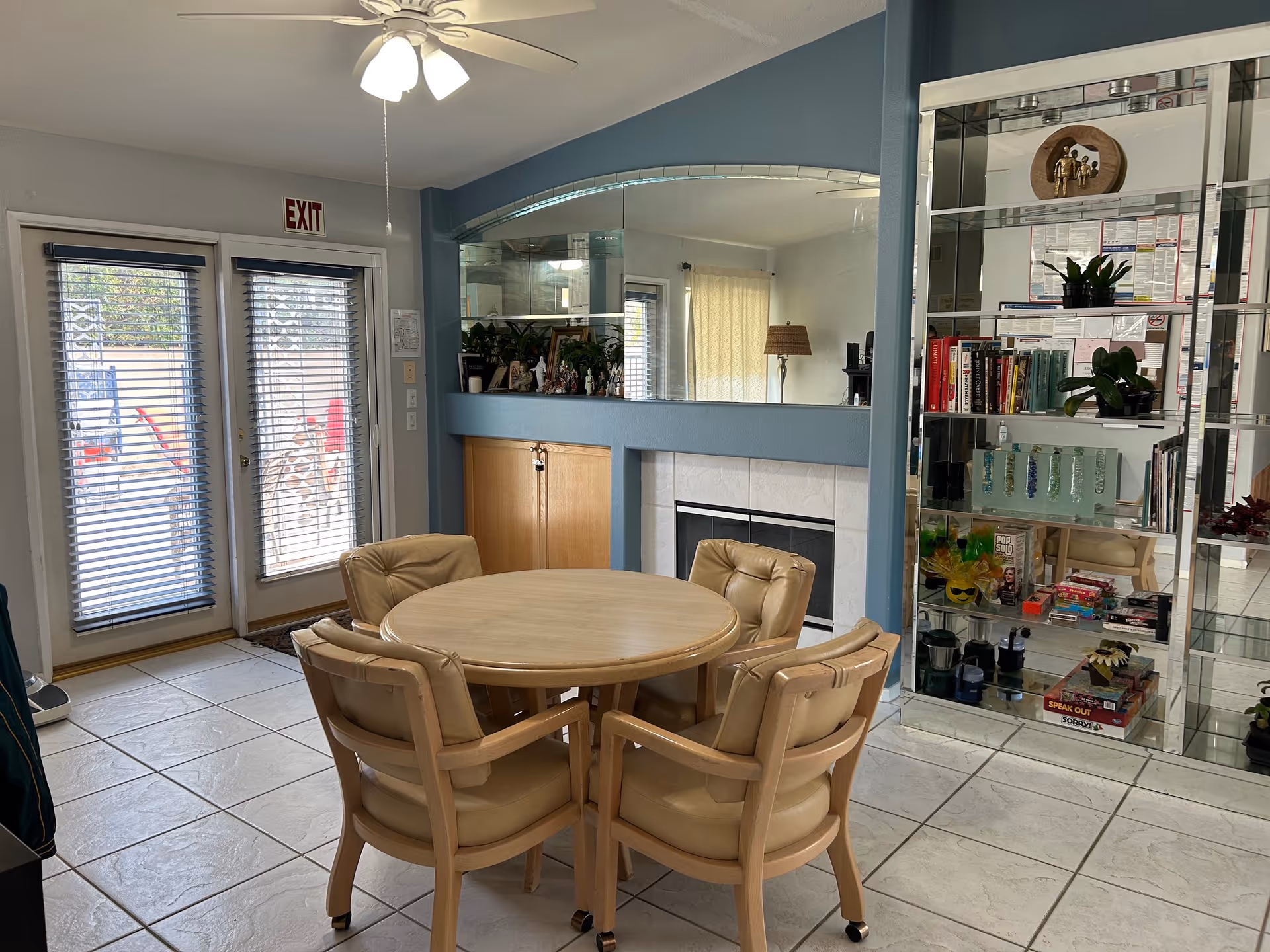 A round dining table with cushioned chairs in a bright senior living dining room.