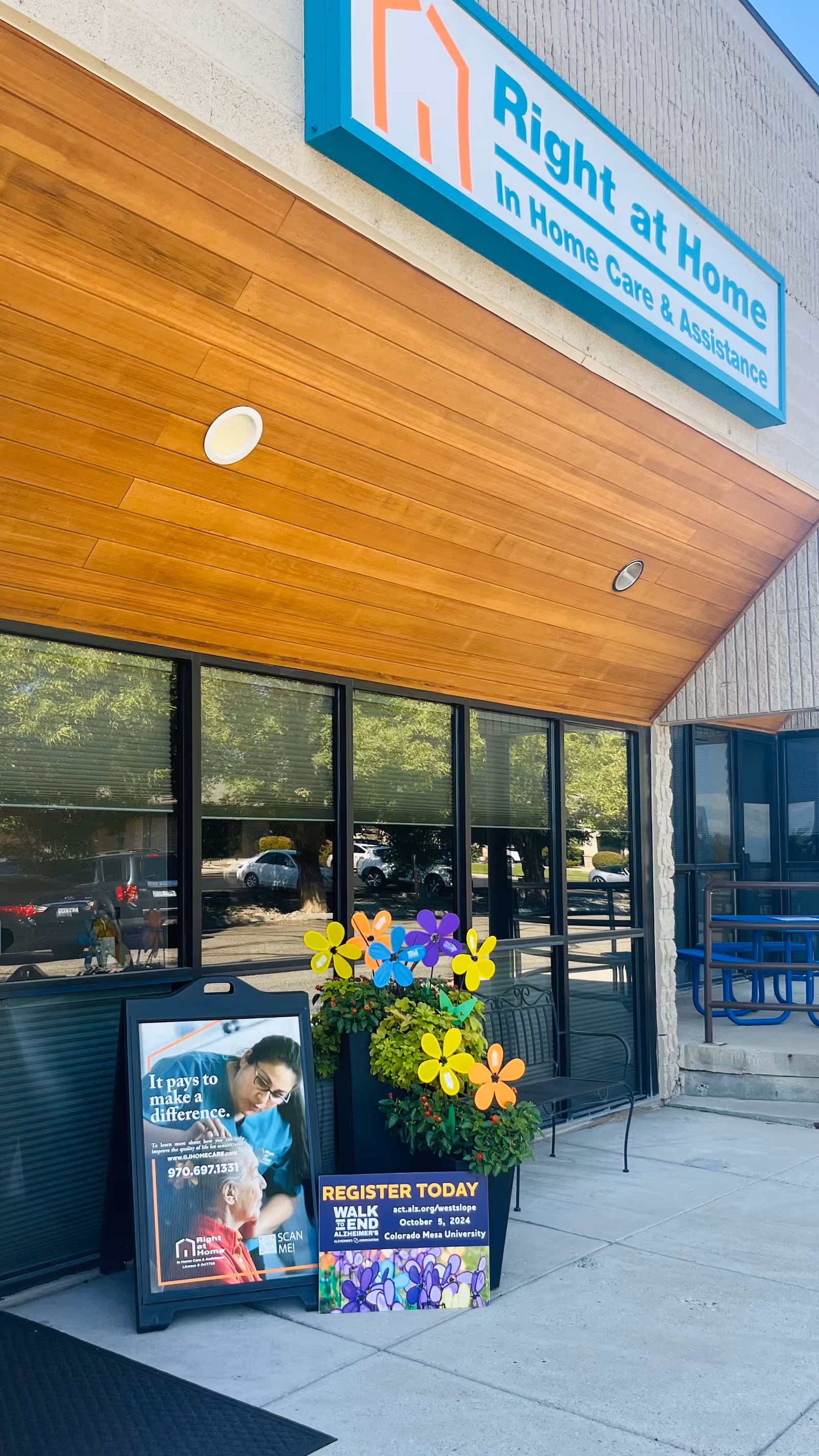 Exterior of Right at Home entrance with wooden awning, glass windows, and colorful flowers.