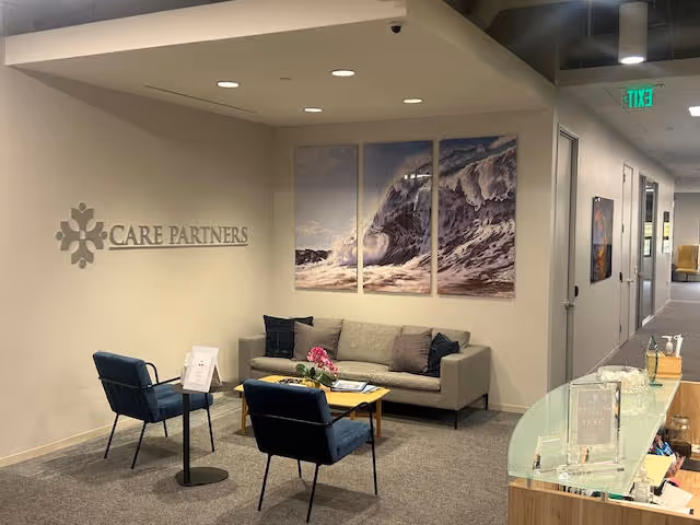 Care Partners At Home lobby area with sofa, chairs, coffee table, and ocean-themed triptych wall art.