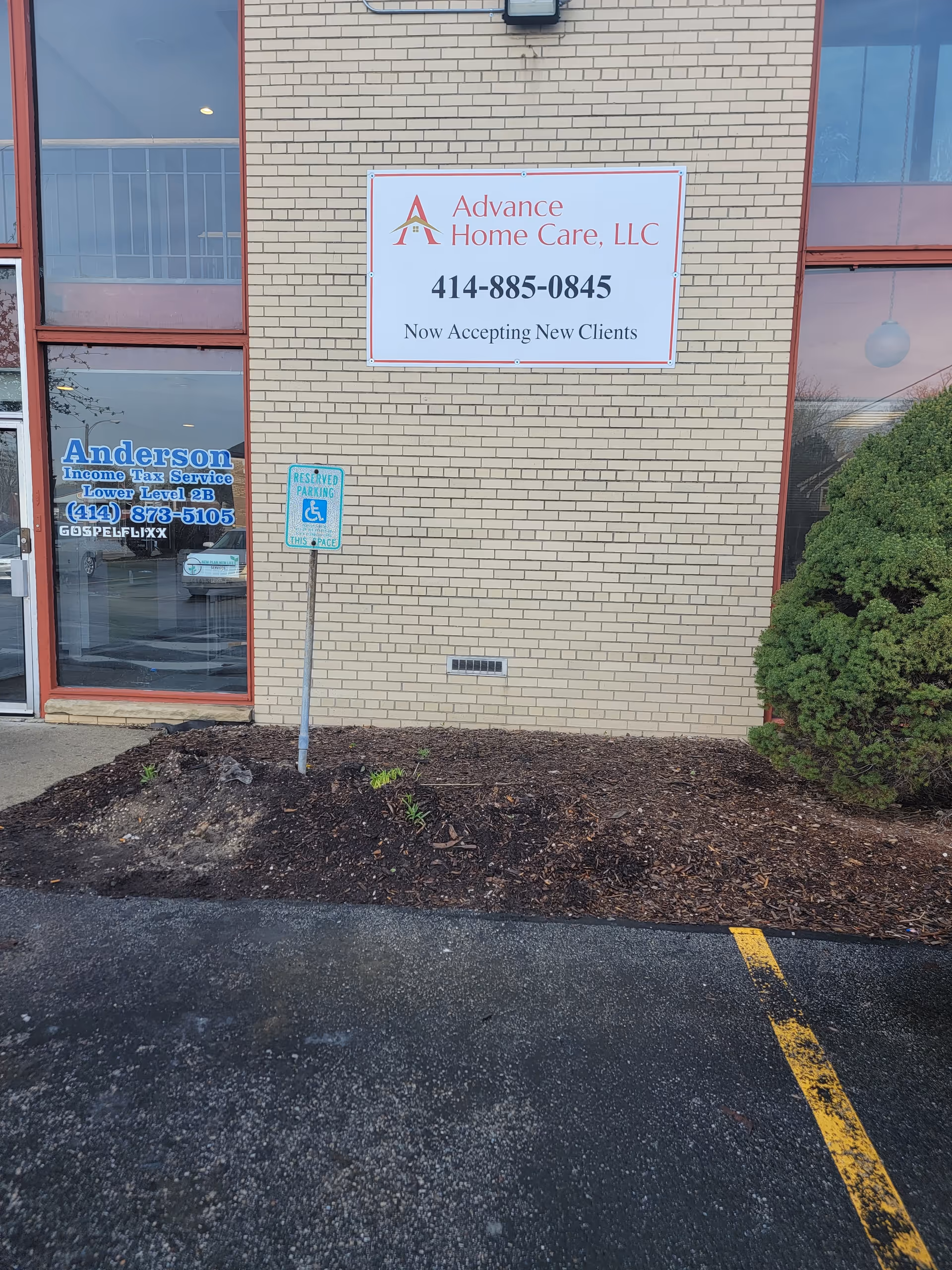 Brick building exterior with a large Advance Home Care, LLC sign and parking.