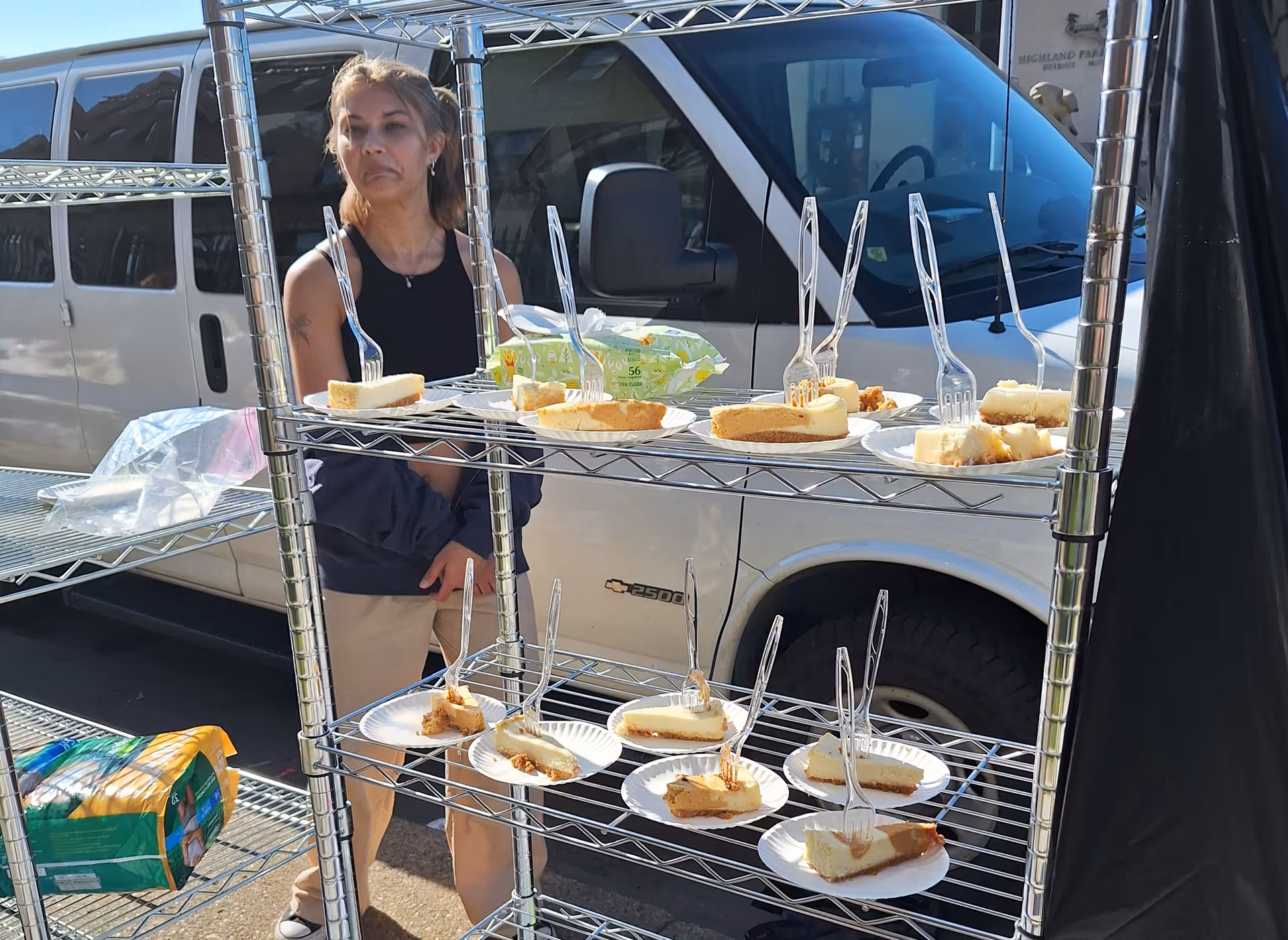 A woman stands beside a metal food rack with slices of cake outside a Kroger Pharmacy
