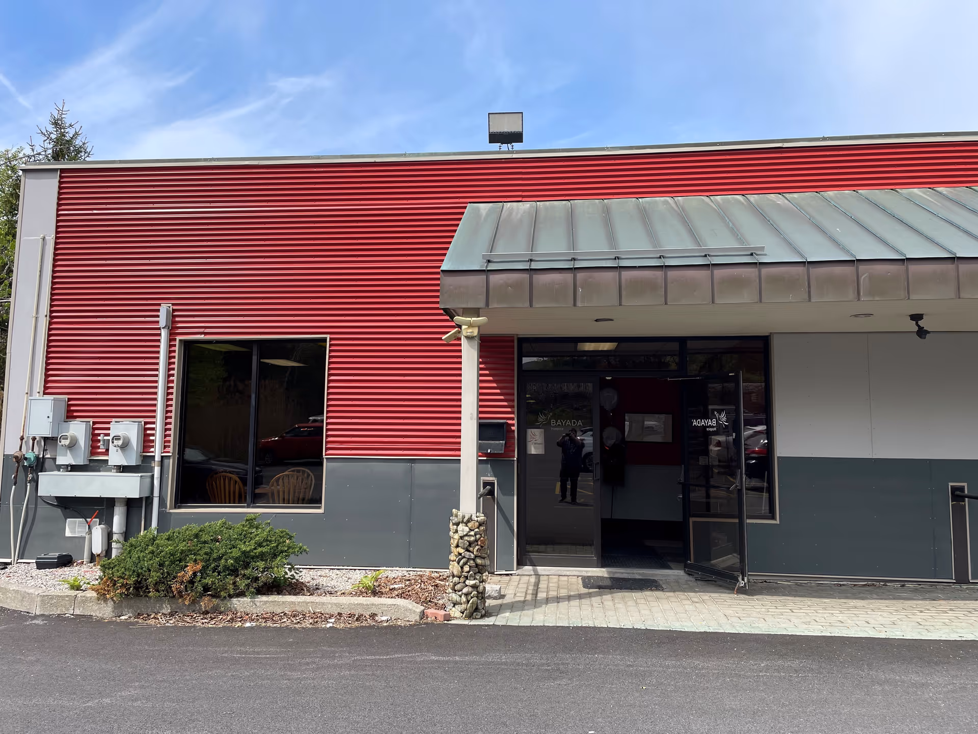 Exterior view of a red BAYADA Hospice building with a glass entrance.
