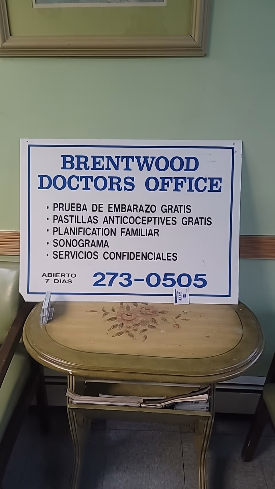 White Brentwood Doctors Office sign on a wooden table in a pastel green hallway