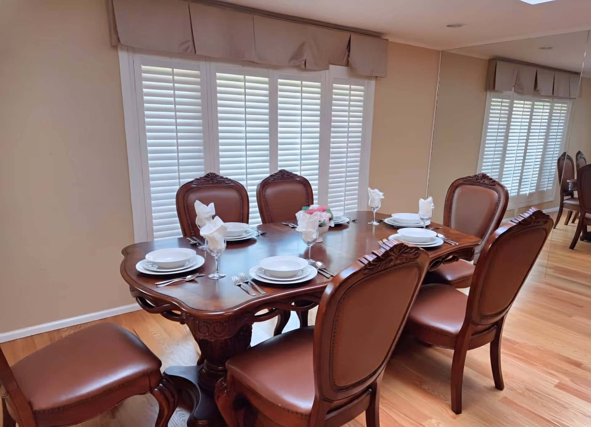 Elegant wooden dining table with place settings in a bright senior living dining room.