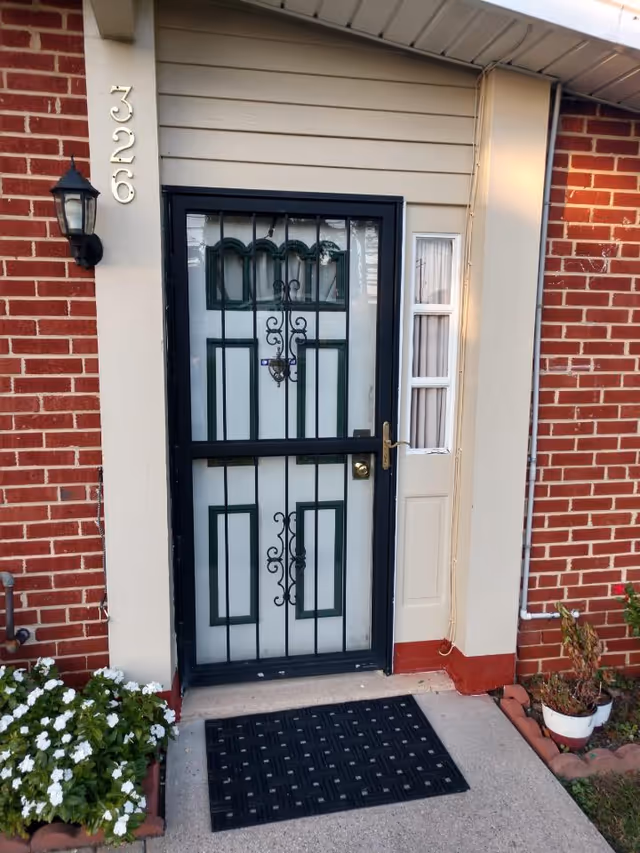 Brick exterior featuring a black metal security door with a small white entry door beside it.