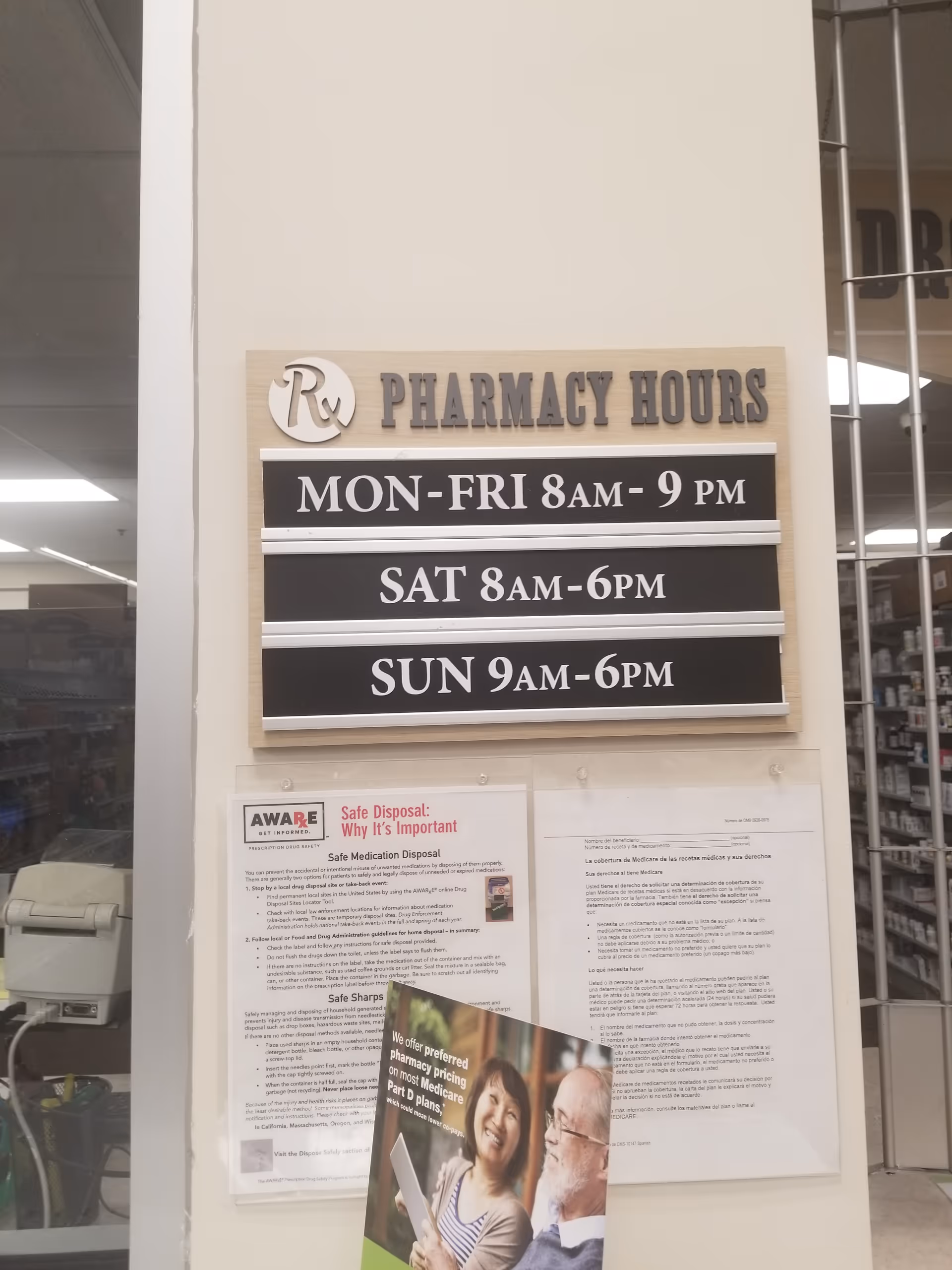 Interior wall displays pharmacy hours board reading MON-FRI 8AM-9PM, SAT 8AM-6PM, SUN 9AM-6PM.