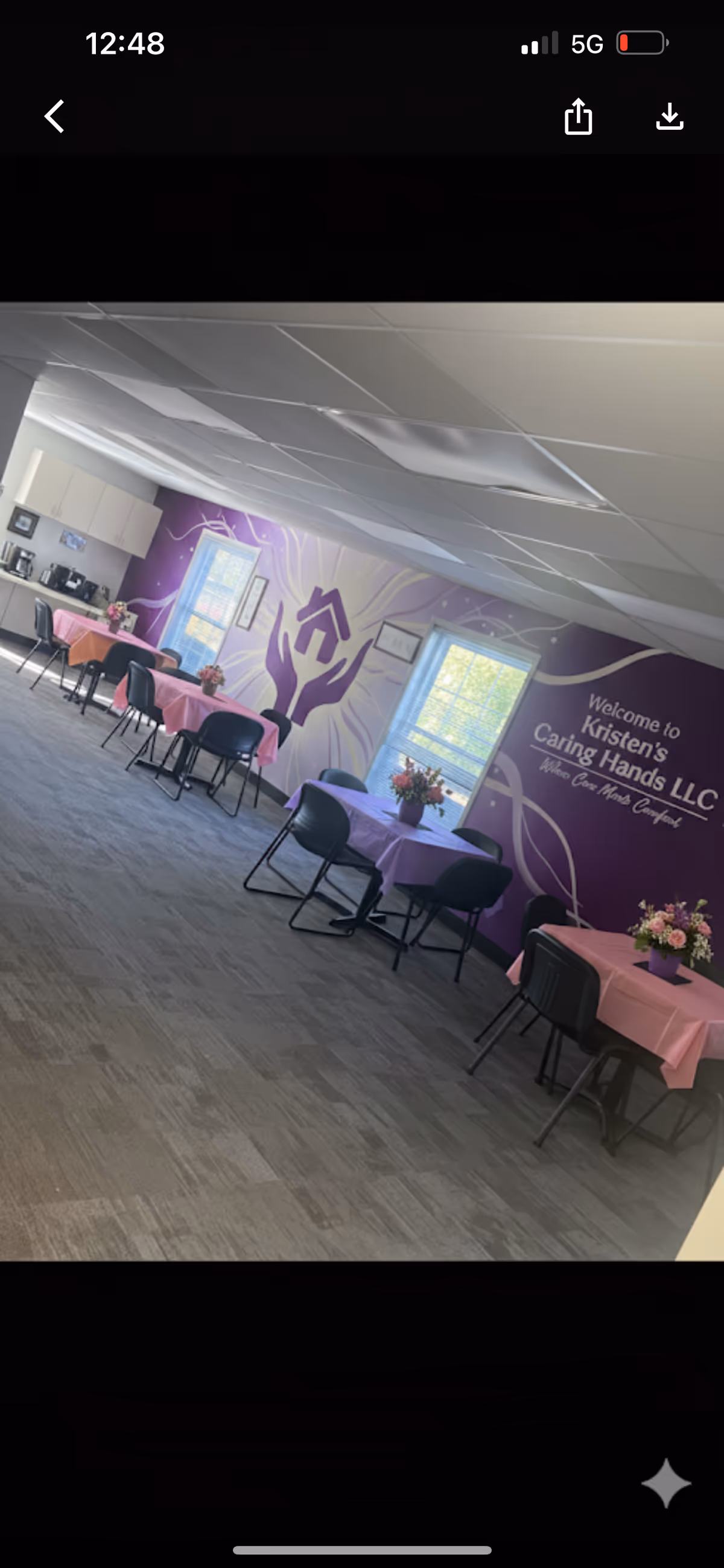 Interior dining area of Kristen's Caring Hands LLC with purple walls and floral centerpieces.