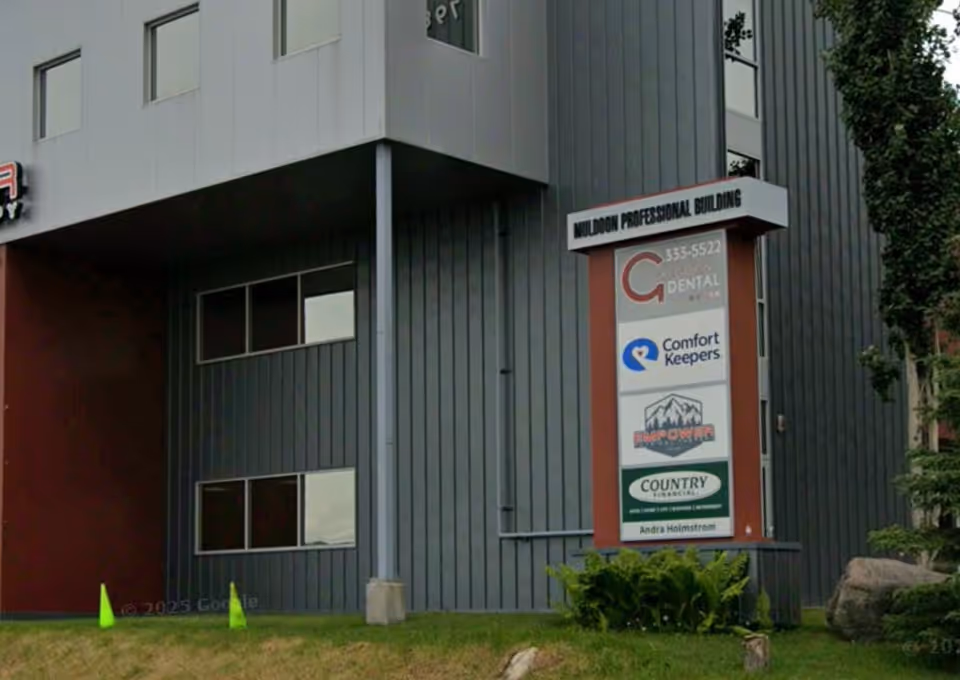 Modern gray building exterior with vertical sign displaying Comfort Keepers logo among other tenants.