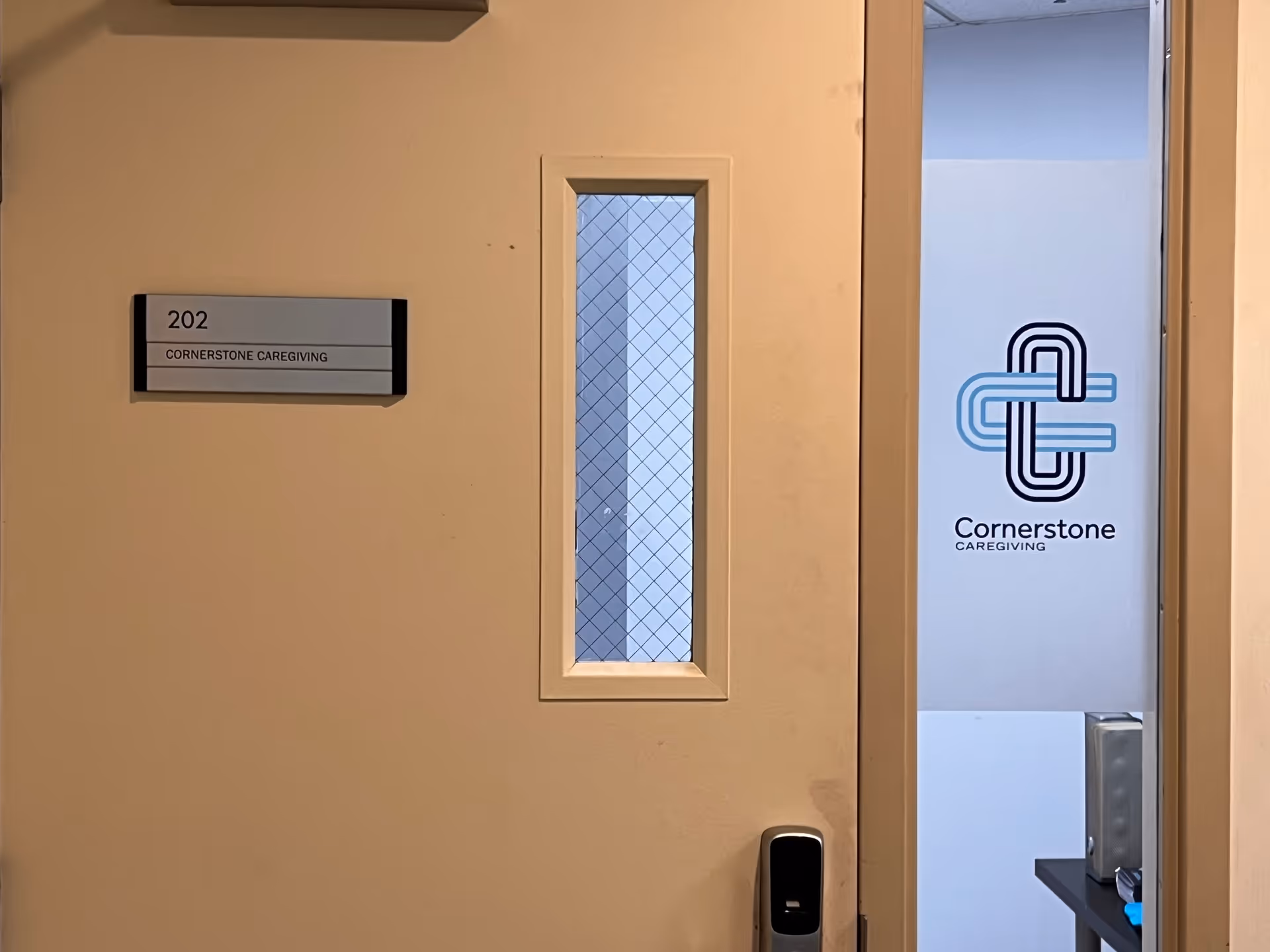 Interior door labeled 202 with Cornerstone Caregiving sign and logo beside it.