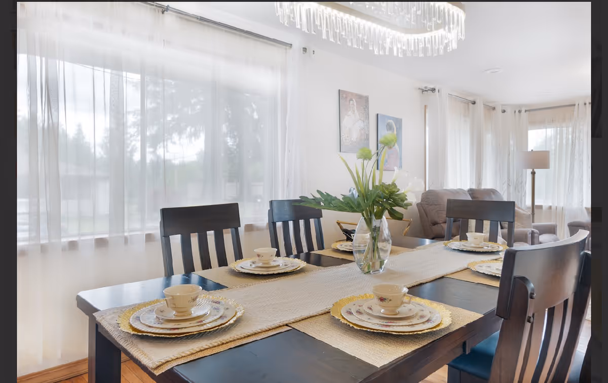 Bright dining room with a four-seat table set with dishes and a vase of flowers.