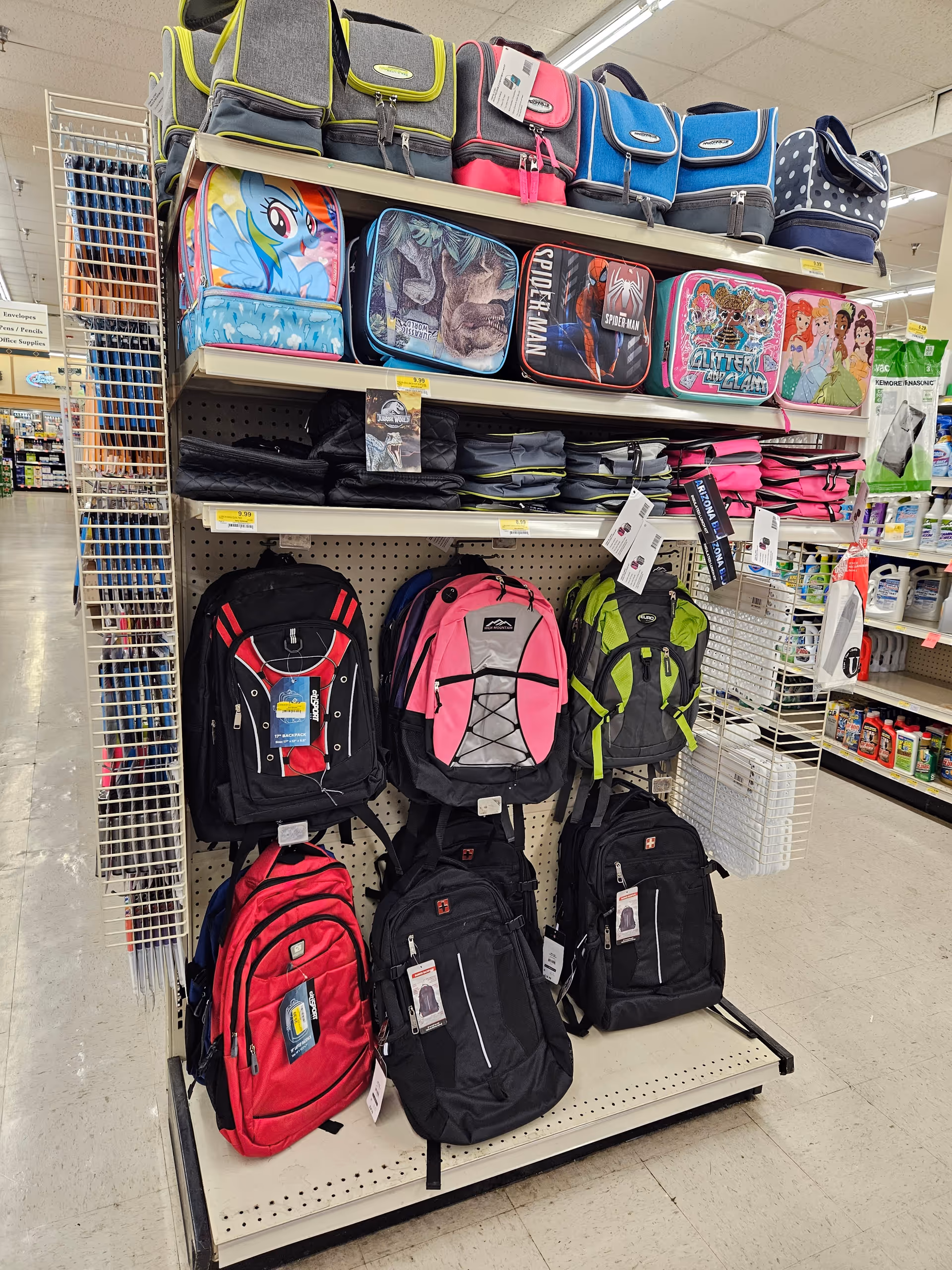 Retail aisle at Discount Drug Mart with colorful backpacks on display.