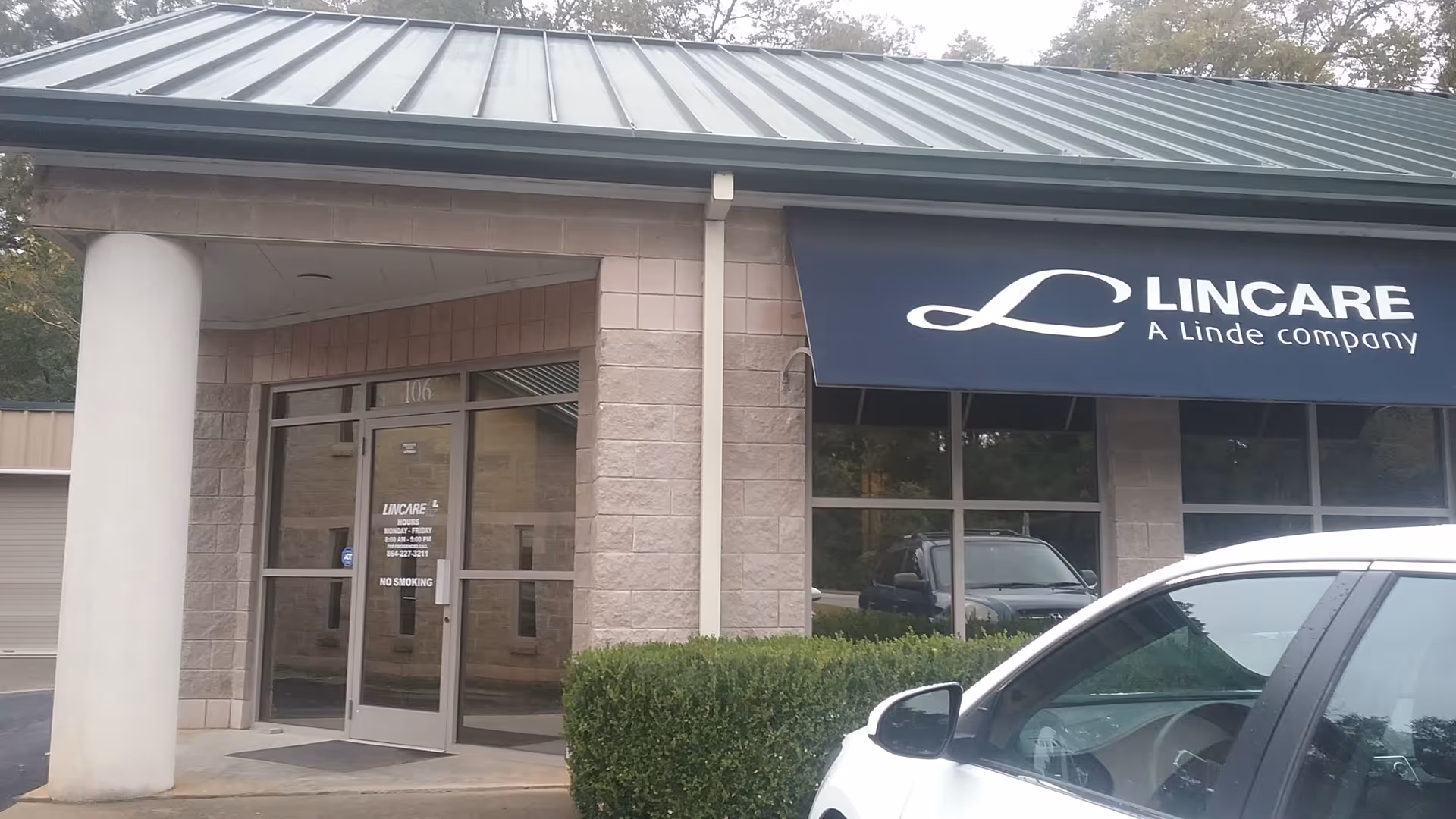 Exterior view of Lincare facility with glass doors, a blue canopy sign, and a parked car.
