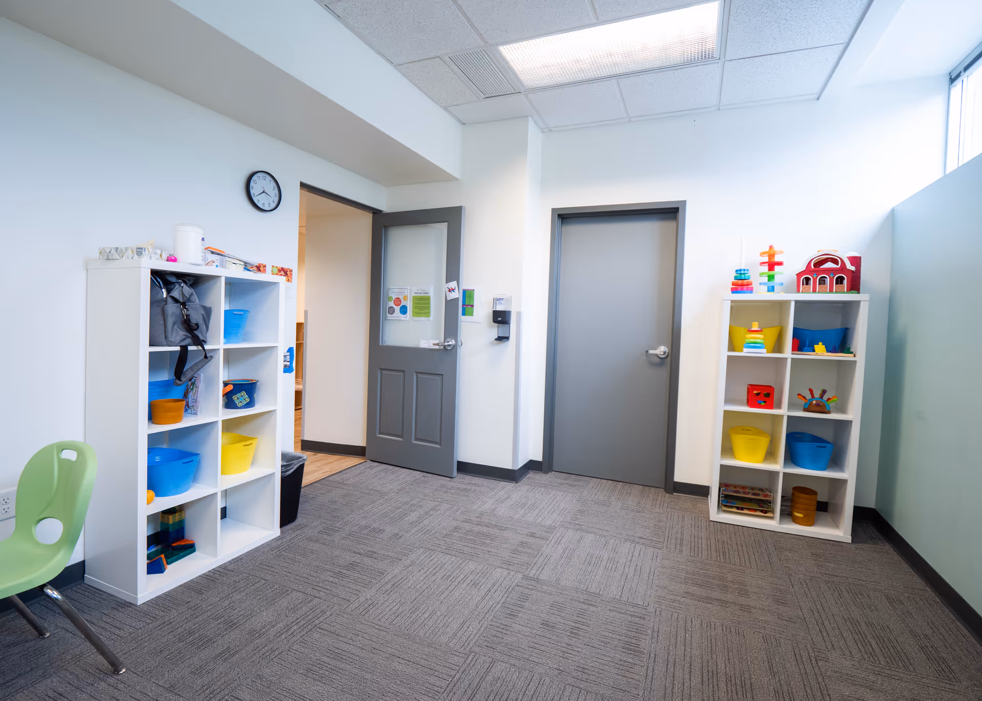 Playroom with shelves of colorful toys and a green chair