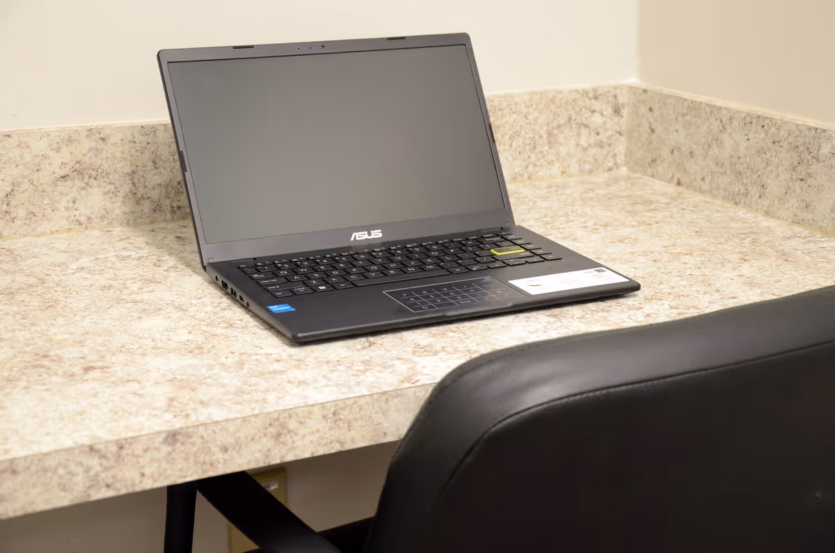 ASUS laptop on a beige speckled counter beside a black chair.