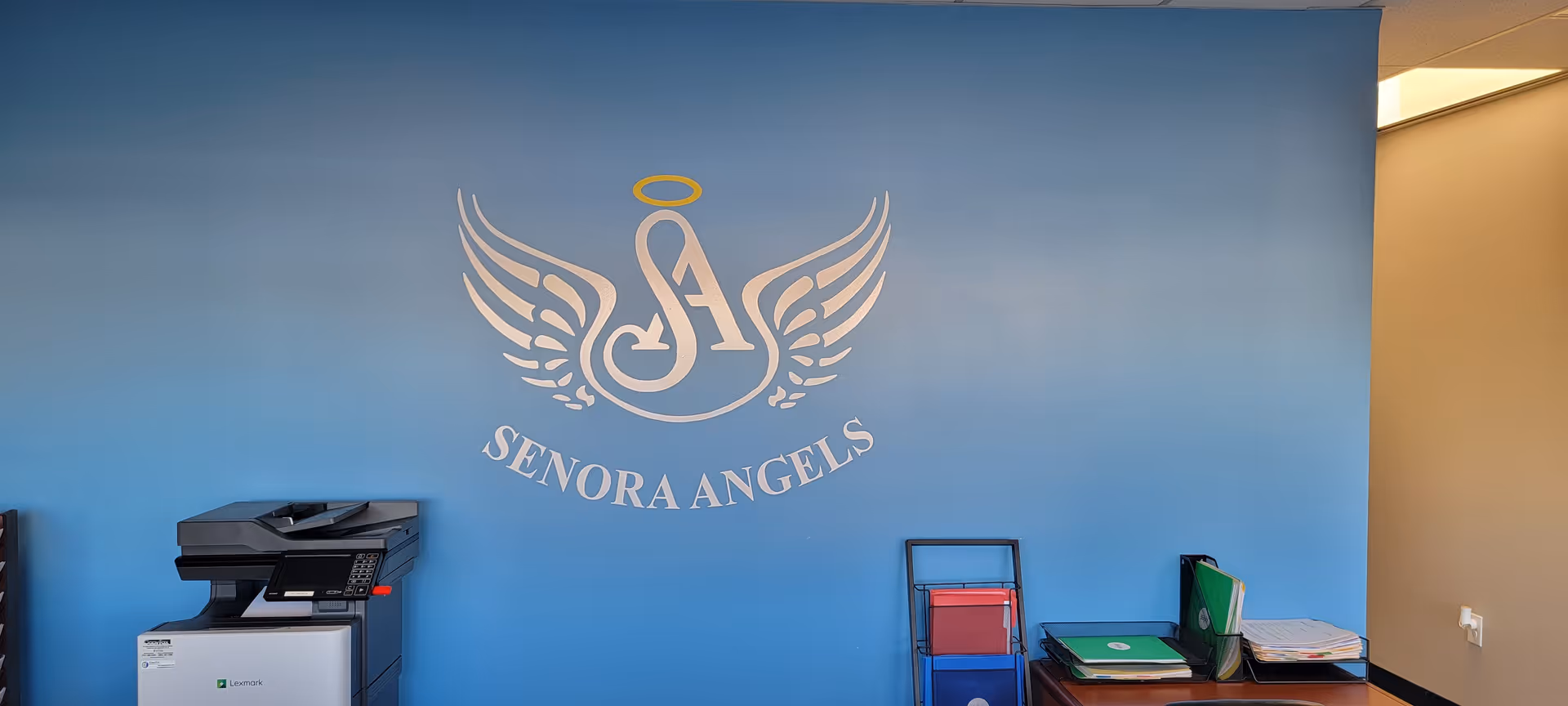Blue wall featuring the Senora Angels logo with wings and halo.