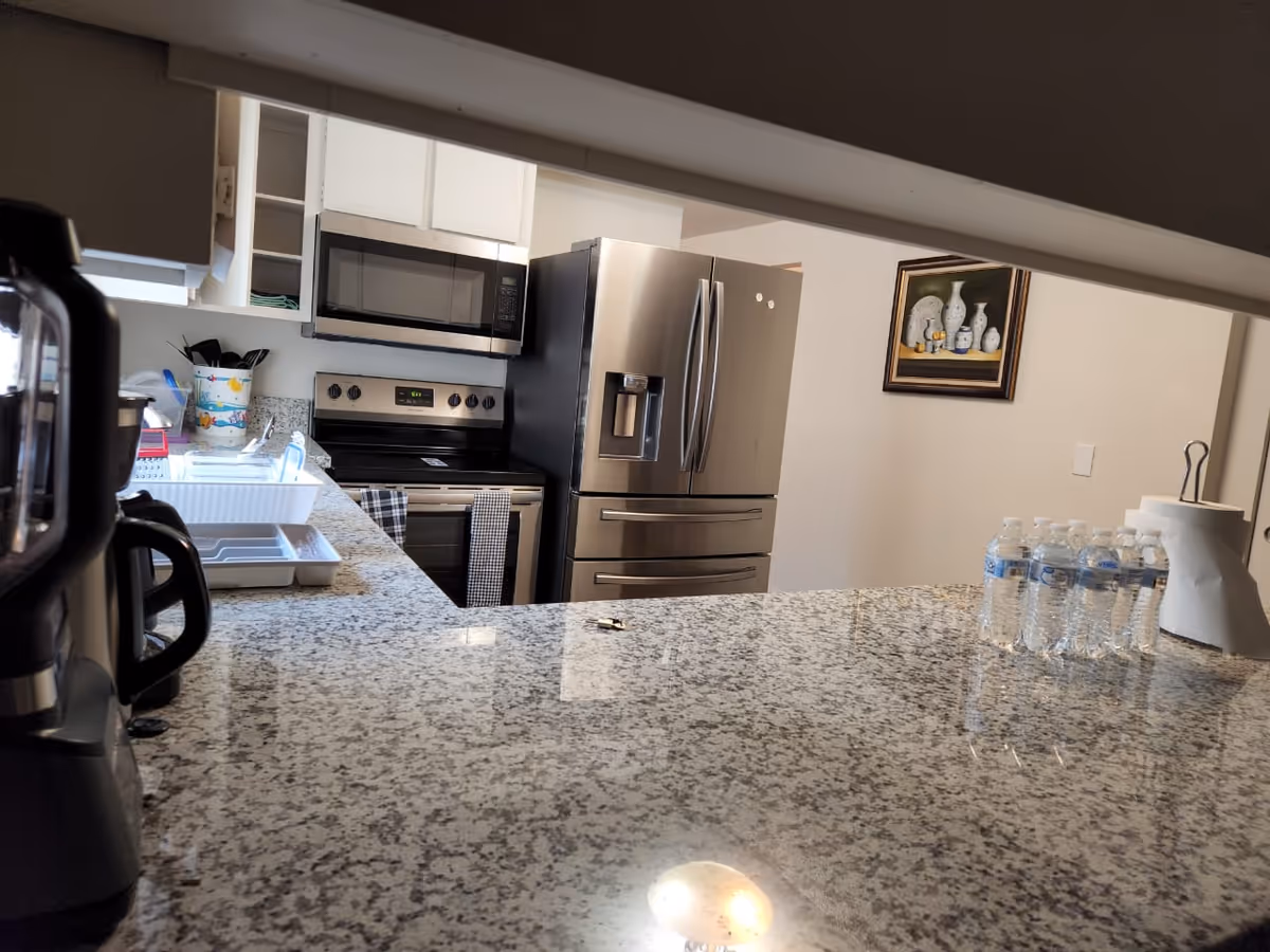 Modern kitchen with granite countertops, stainless steel appliances, and bottled water on the counter.