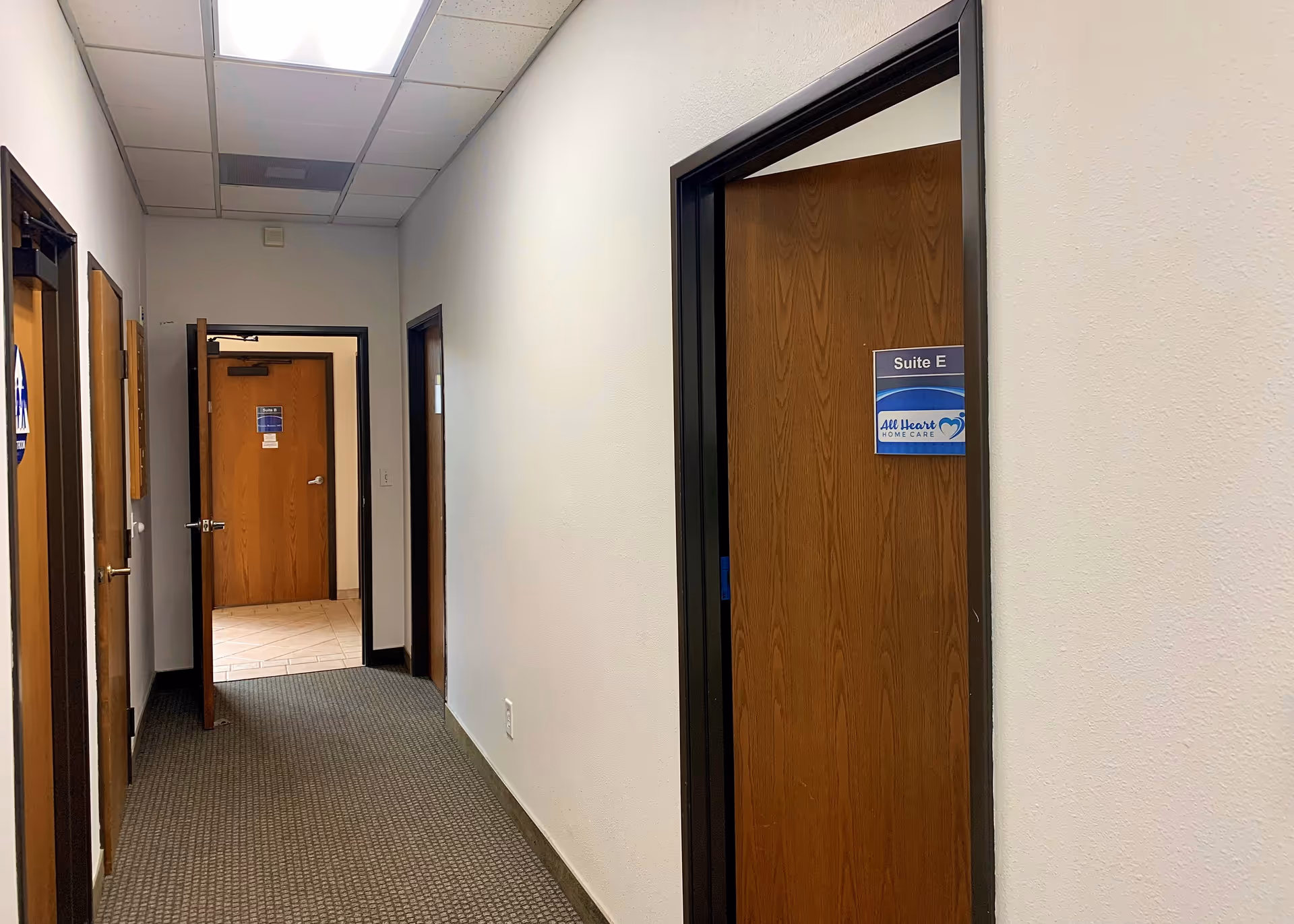 Long hallway in a senior home care facility with multiple closed doors.