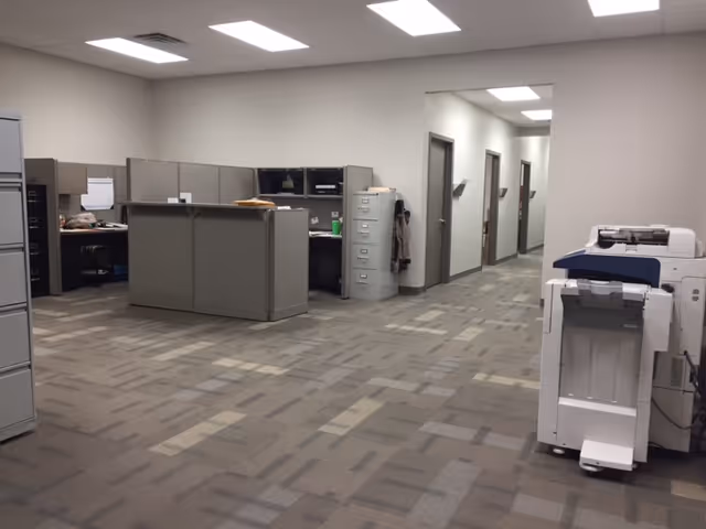 Office-like facility workspace with cubicles, filing cabinets, and a large printer/copier.