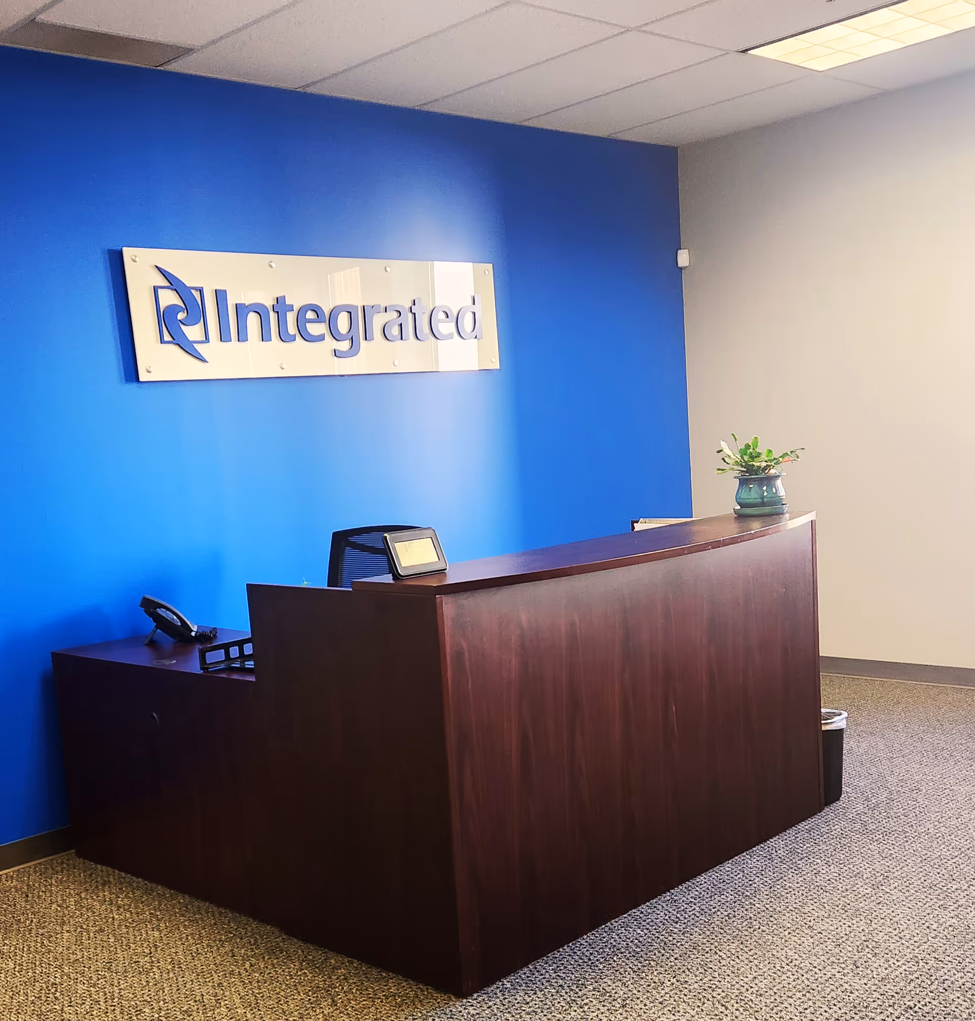 Reception desk against a blue wall with an Integrated sign in a lobby.