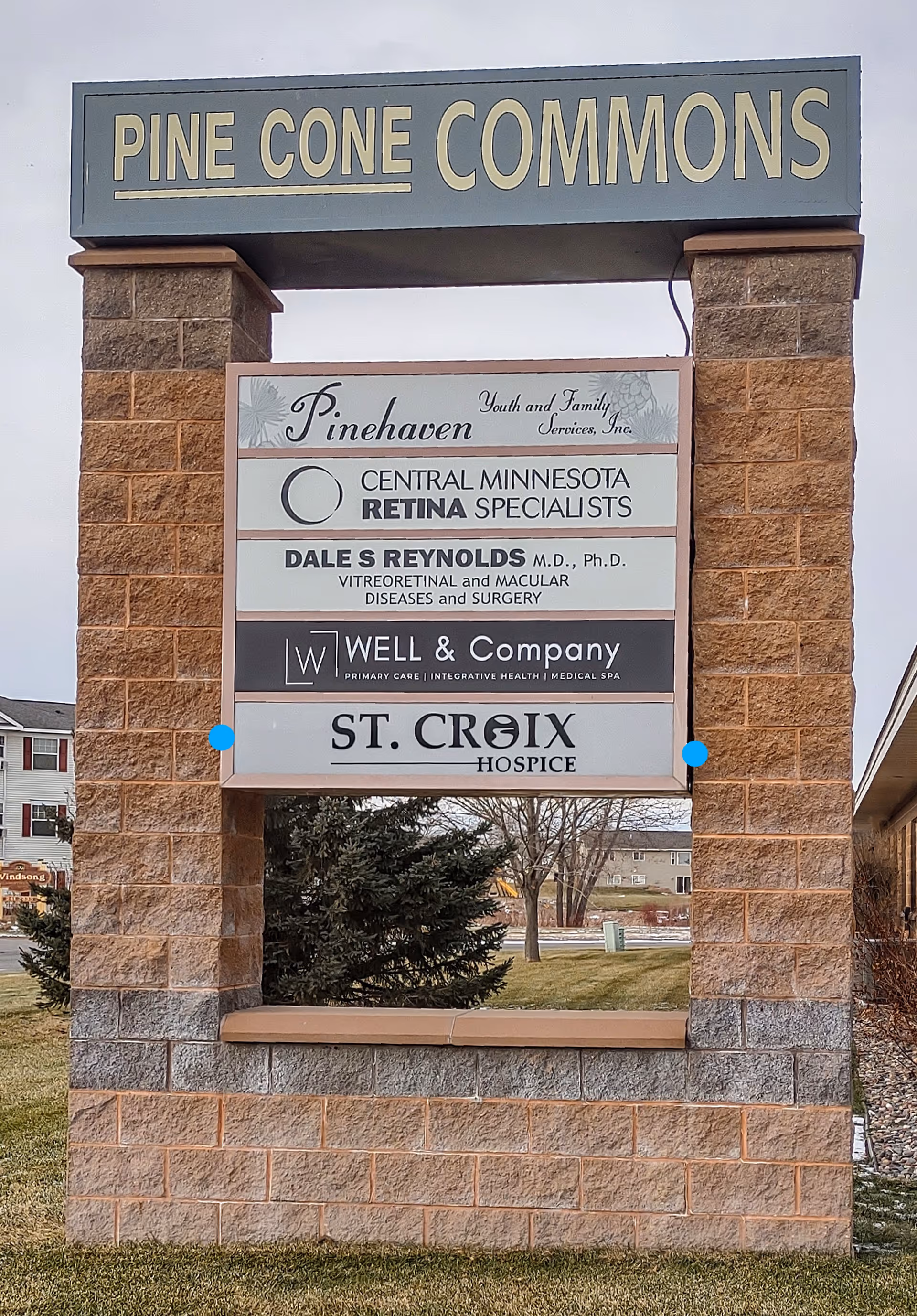 Stone sign structure displays Pine Cone Commons and St. Croix Hospice outdoors.