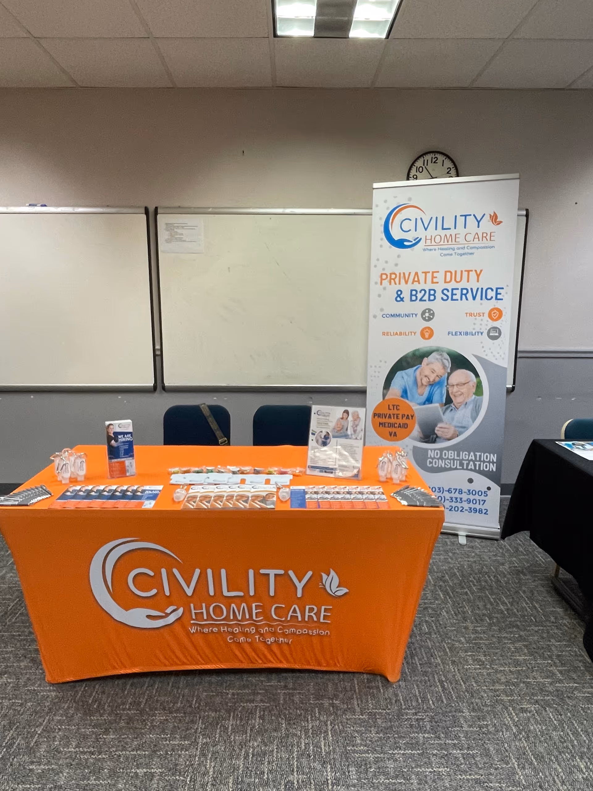 Indoor promotional booth for Civility Home Care with orange table and banner.