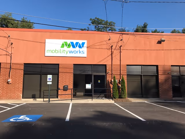 Brick commercial building with MobilityWorks sign and large glass storefronts along a parking lot.