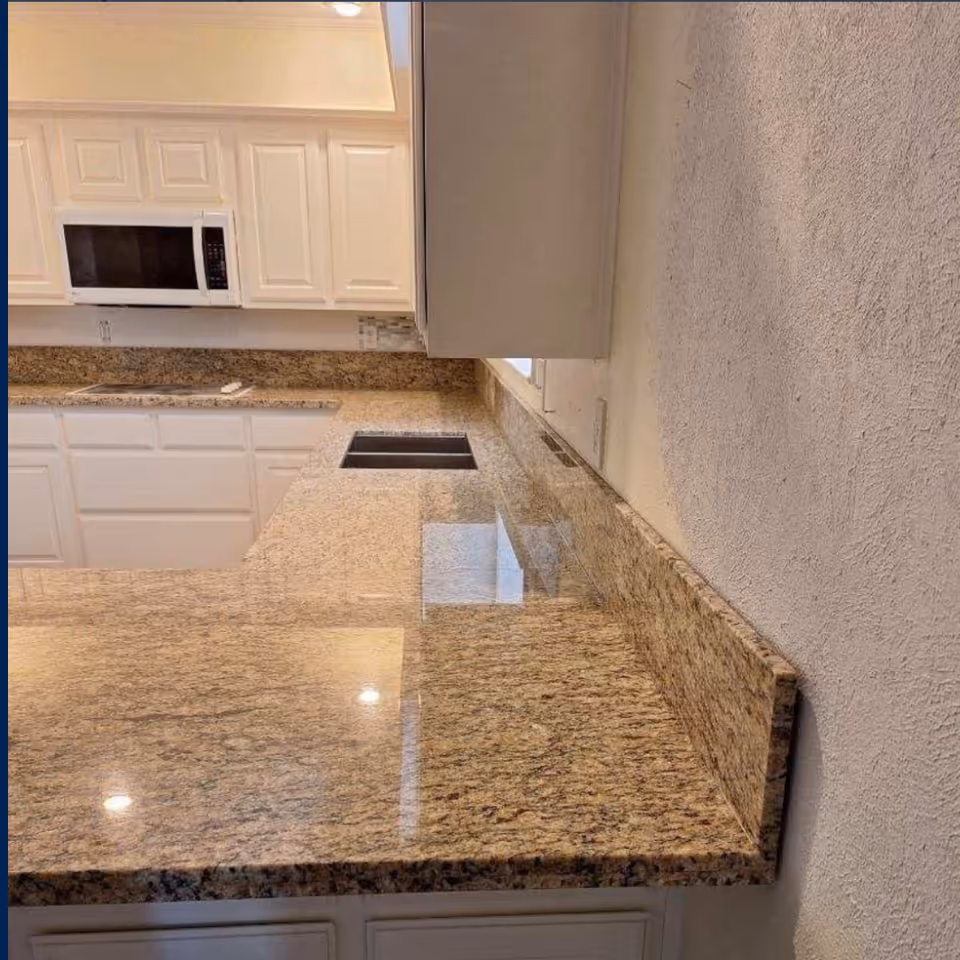 White kitchen with granite countertops, cabinets, and a microwave.