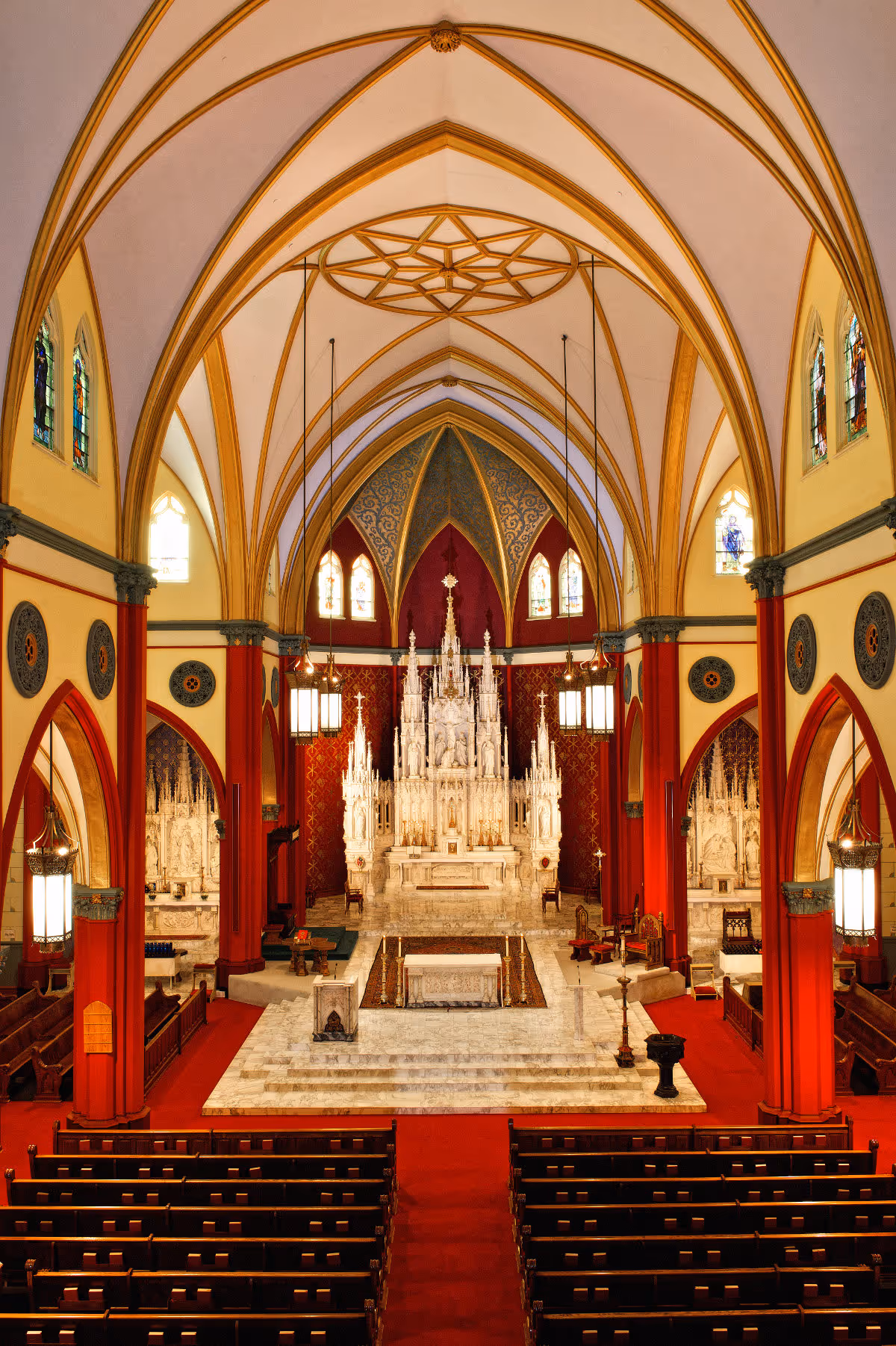 Interior of a grand chapel with ornate altar, arches, and pews.