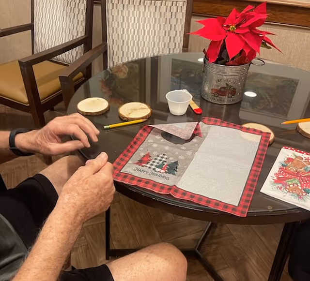 Hands craft at a round glass table with holiday placemats and a poinsettia