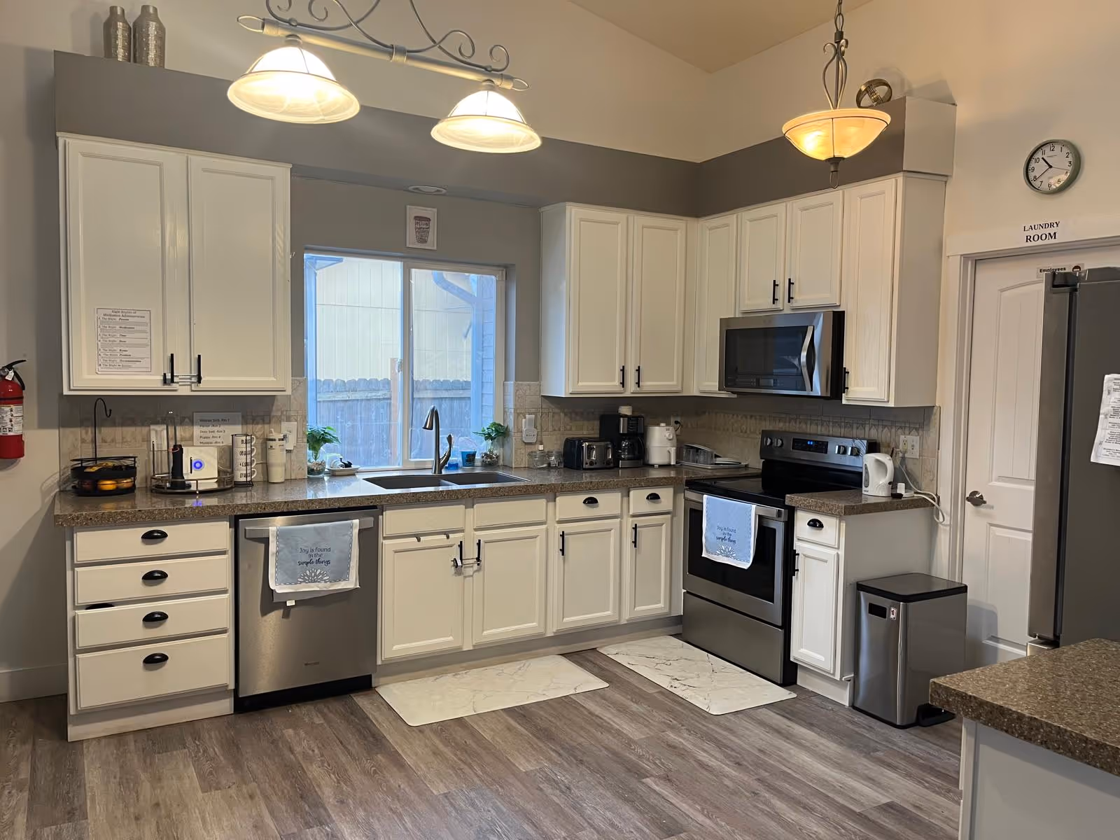 Bright kitchen in a senior living facility with white cabinets and stainless appliances.