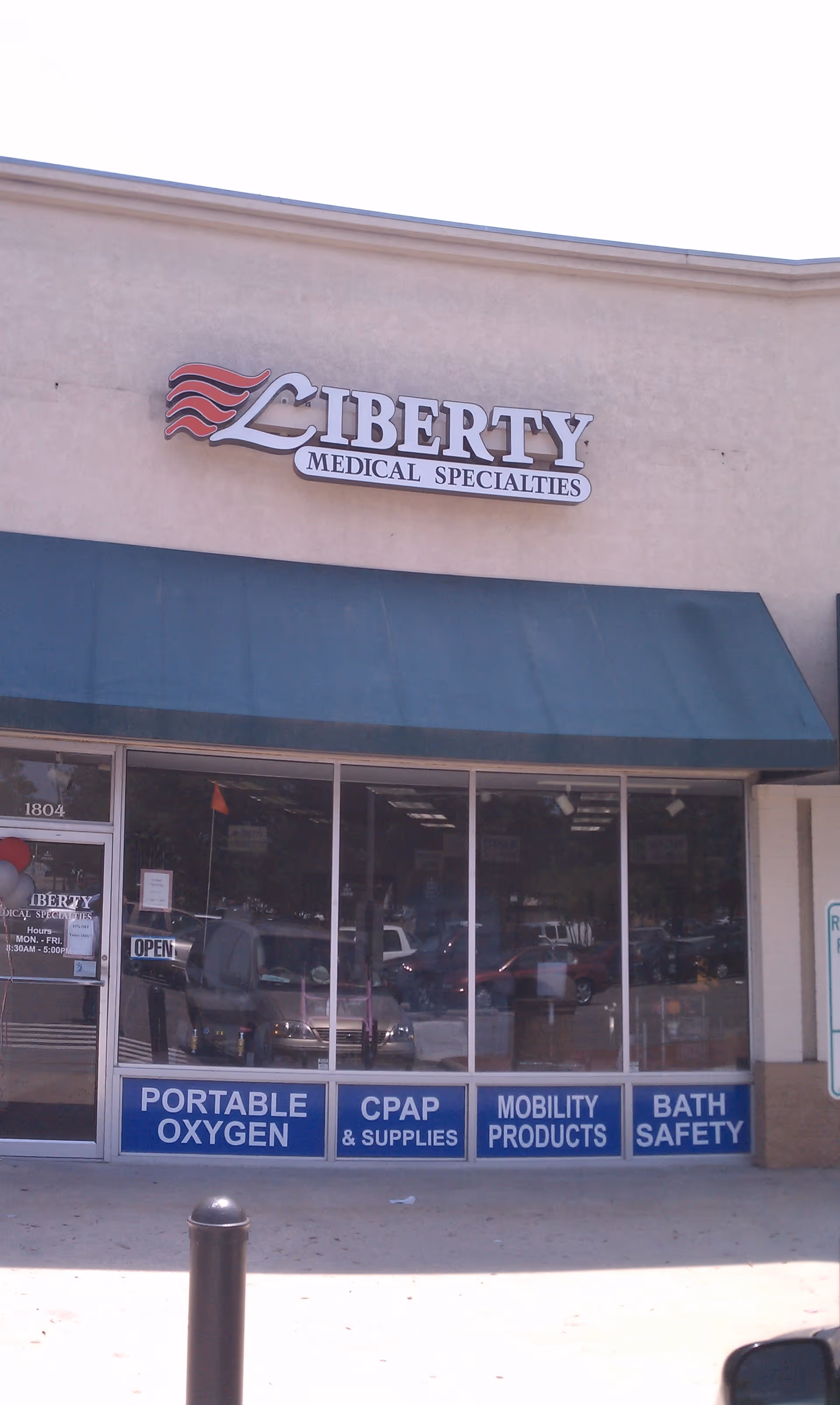 Exterior storefront of Liberty Medical Specialities with blue awning and signs in windows.