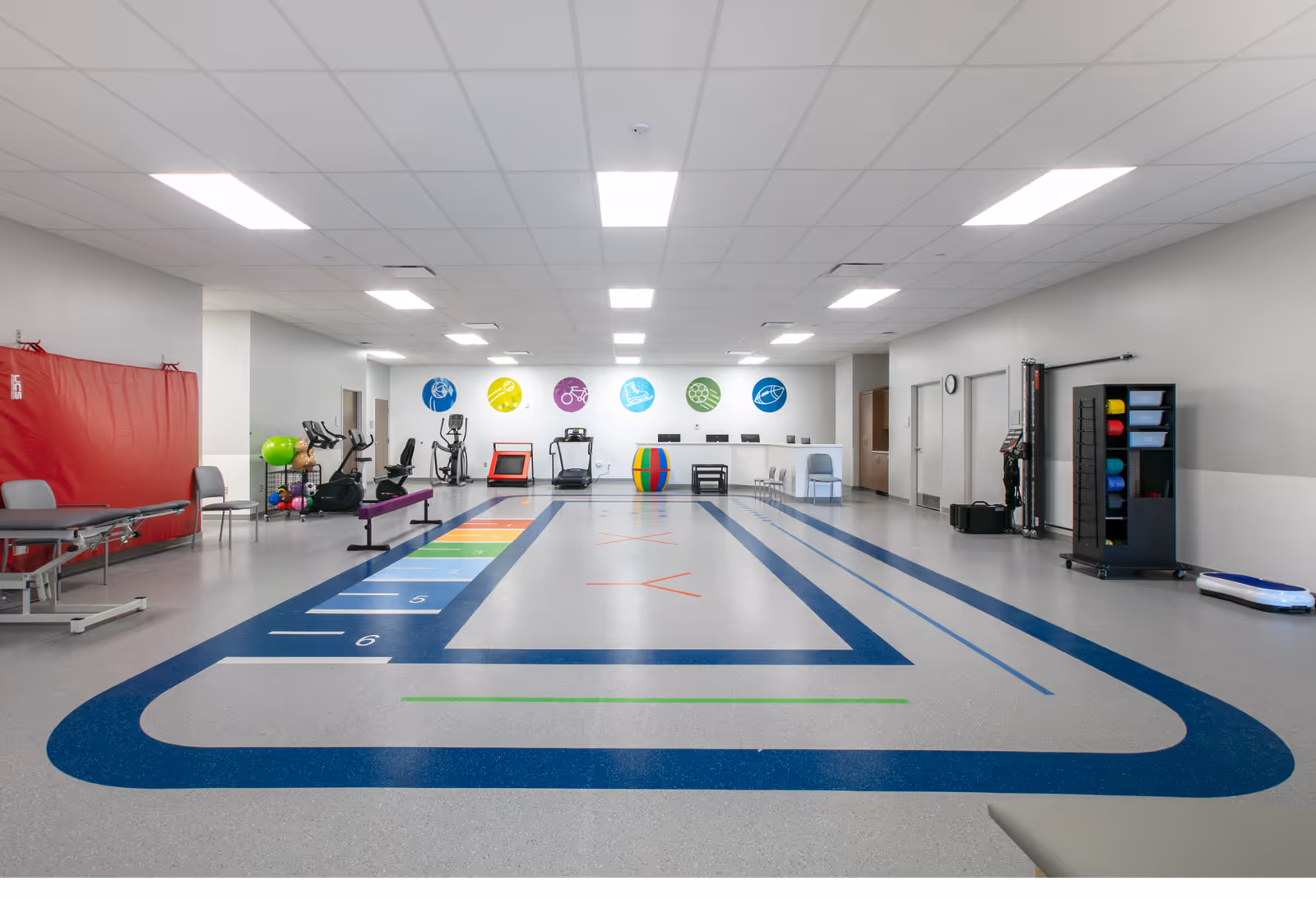 Bright rehabilitation gym in a senior care center with exercise equipment and a running track