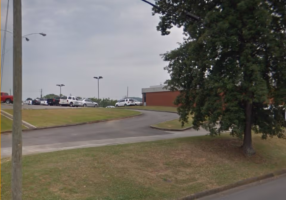 Exterior view of a LINCARE senior facility with a curved driveway and parked cars.