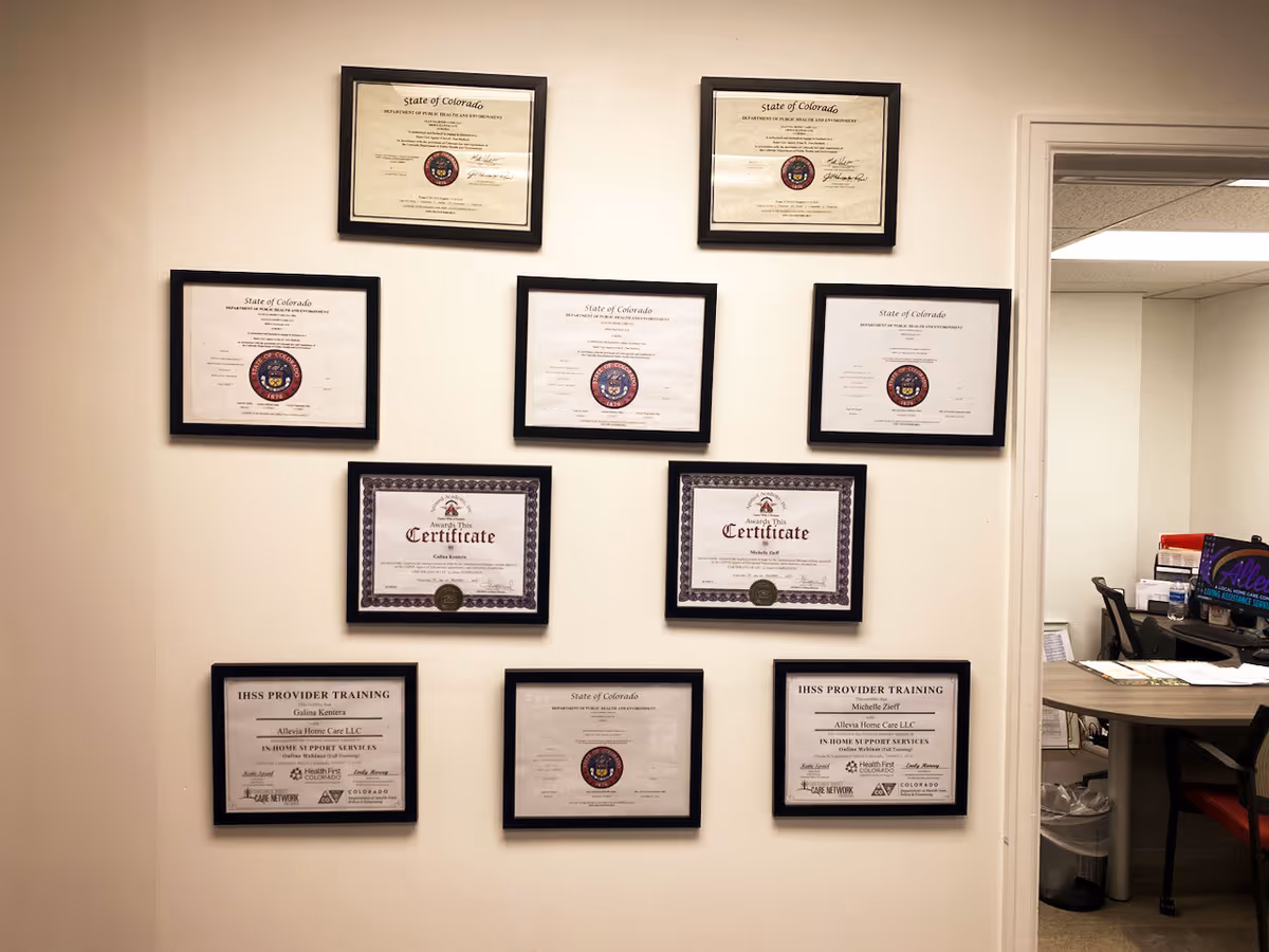 Wall with numerous framed certificates and a right-side office area.