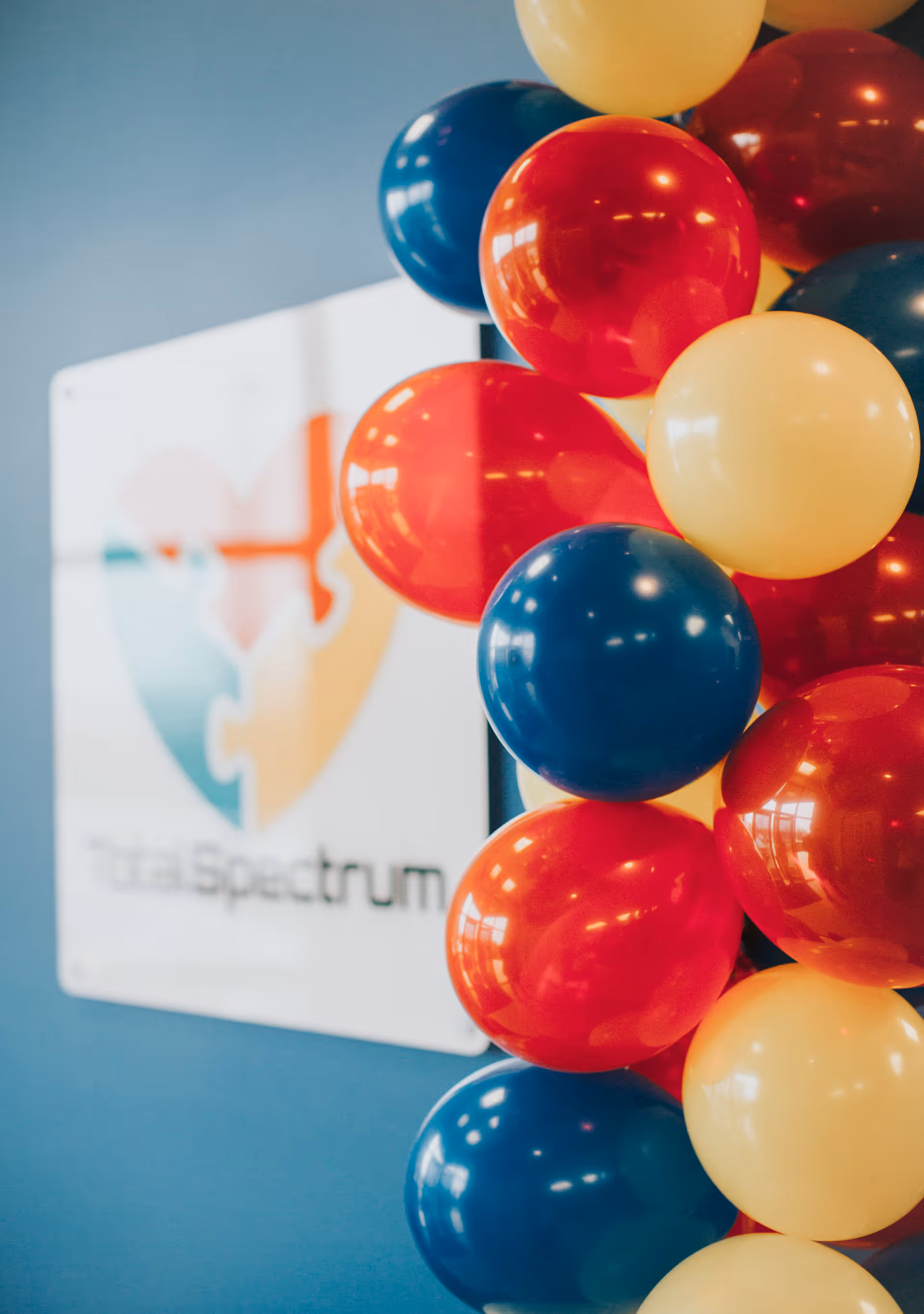 Colorful balloons cluster beside a Total Spectrum ABA sign on a blue interior wall